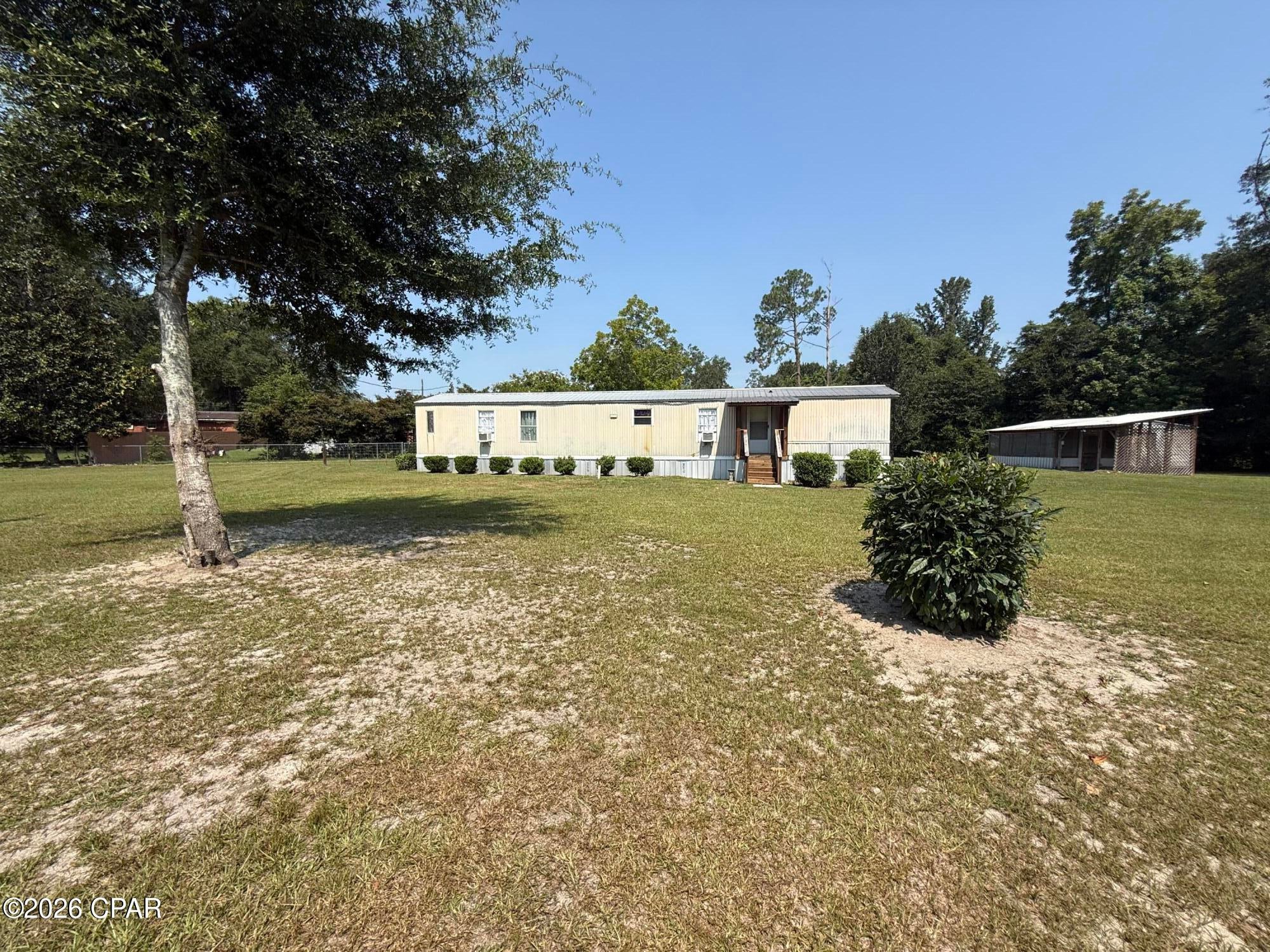 Welcome to this well-maintained 2-bedroom, 2-bath 1989 single-wide mobile home situated on a beautifully manicured, fully fenced 1-acre lot with a gated entrance, offering privacy and room to enjoy the outdoors. Located on a quiet street within the city limits, this property combines peaceful living with the convenience of city amenities.

The home features central heating and cooling, plus three additional window units with heat and air for added comfort and flexibility.  Unwind on the spacious covered back porch, perfect for entertaining or enjoying the peaceful surroundings.

The primary suite offers a large walk-in closet, a new vanity, updated shower insert, and a newer bathtub. Additional updates include a newer water heater, newer front porch, and a durable metal roof approximately 6 years old.

Outside, you'll find an attached one-car covered parking area and a versatile outbuilding with a screened-in porch with a concrete foundation, water accessibility, and electricity already in place. Whether you need extra storage, a workshop, or hobby space, this building offers excellent potential.

The property is served by city water and a septic system, making it an excellent opportunity for anyone looking for affordable country-style living with the convenience of being in town. Washer and dryer convey! Looking for cash buyer!