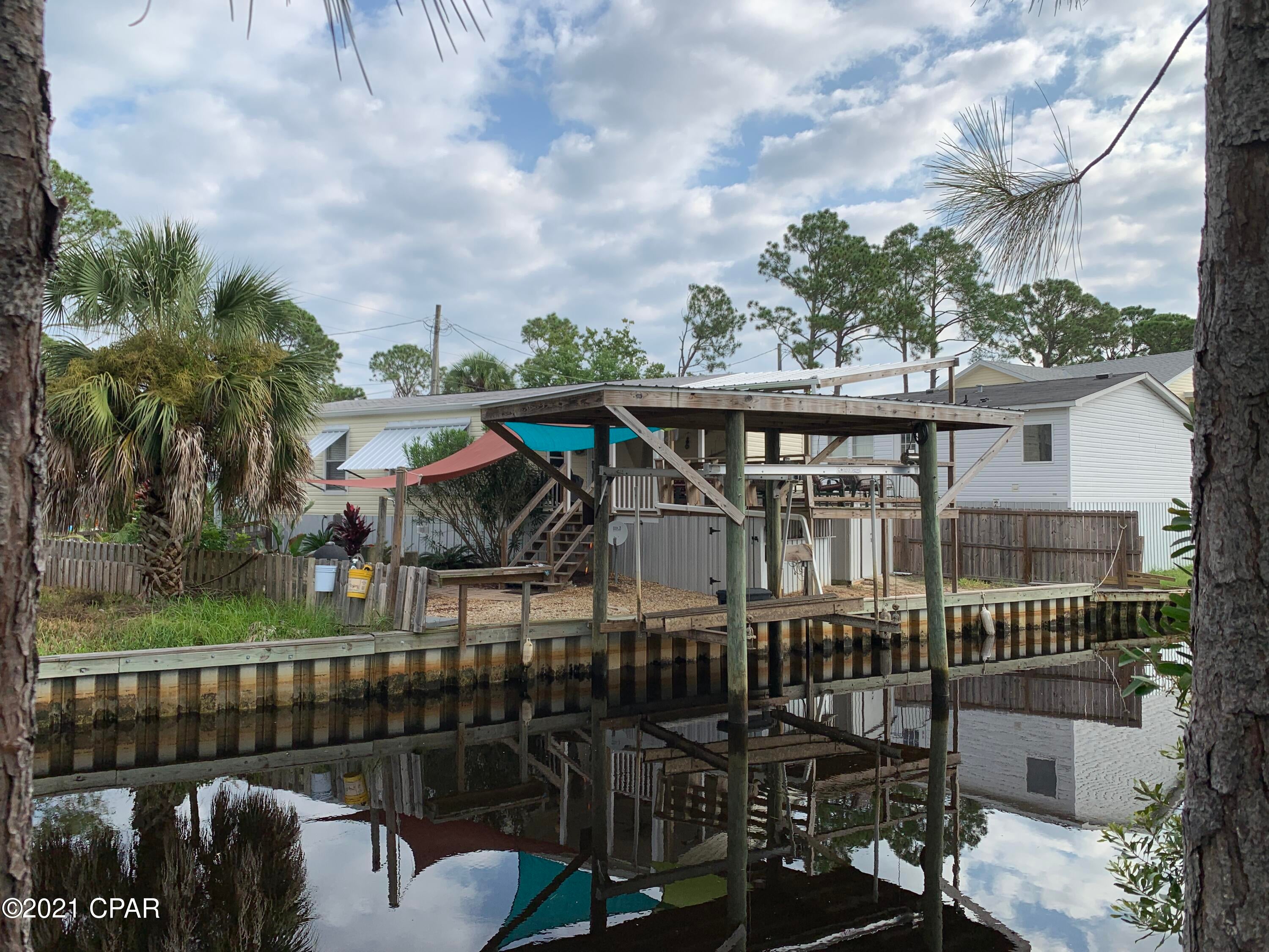 Canal Front Living With Just A Short Boat Ride To Shell Island And The Gulf Of Mexico. If you have been looking for an affordable canal front home just minutes from some of the worlds most beautiful beaches, I have the home for you!  This 2017 manufactured home has an open floor plan, LVP flooring, large open kitchen, split bedrooms with a large master bath.  Outdoor living is what the owners focused on with a covered porch, large deck with a tin roof, an abundant amount of tropical landscaping, grilling area, outdoor shower and an extremely nice covered boat lift right outside your back door.  The canal has a very nice seawall in place andthere is room for an additional boat lift if needed.