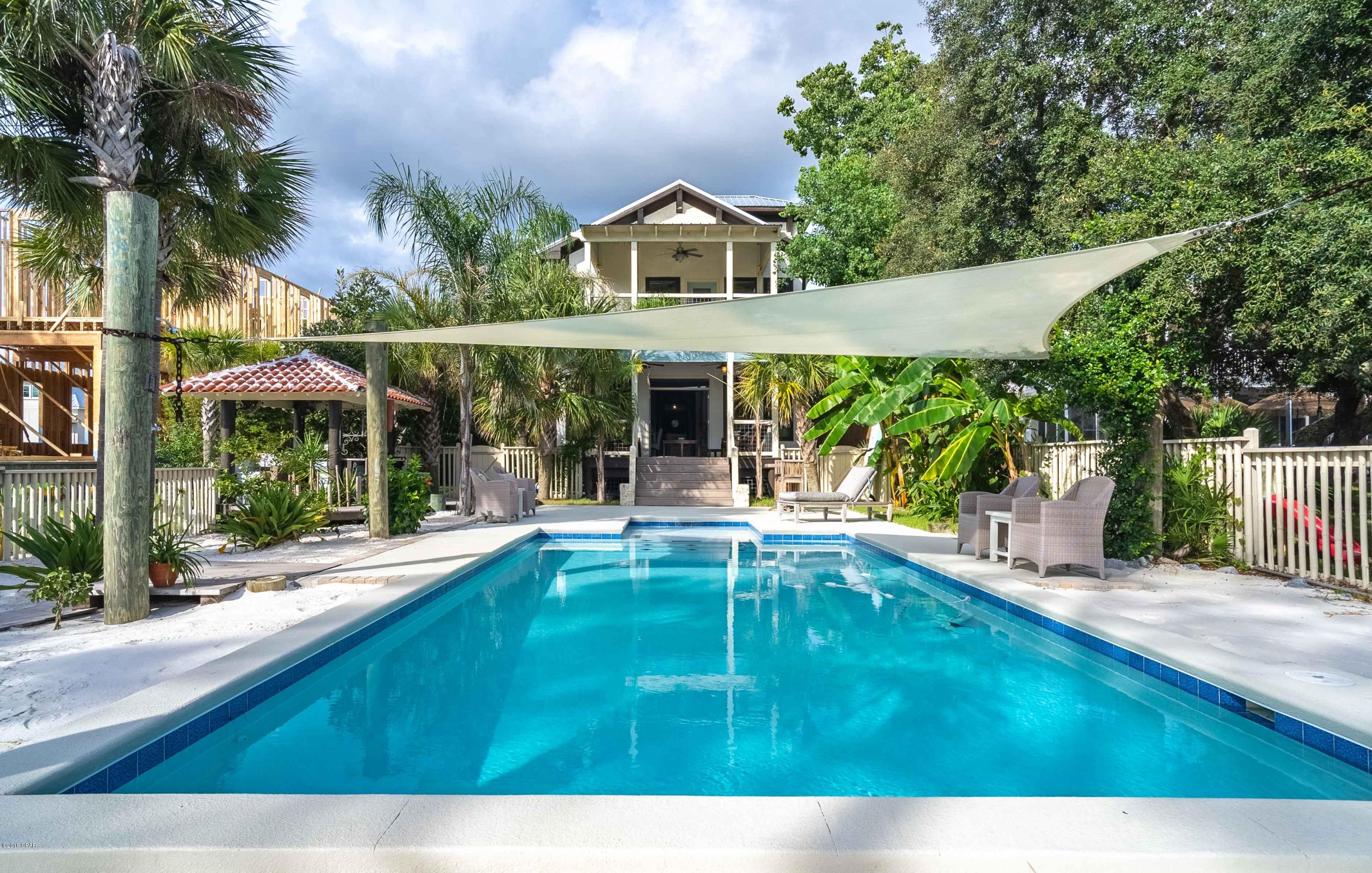 Imagine owning your own piece of tropical boating paradise in this completely custom built home that would make most celebrities envious. The home sits directly on the North side of the Lagoon with deep water and is just a short boat ride to the gulf. It is being offered furnished (minus small exclusion list) in addition to that, the seller is selling the lot next door with the home, please inquire for more details. It is truly a one of a kind getaway that features reclaimed hand built cabinets, hand scraped solid 7/8'' hardwoods throughout, custom handmade doors and hardware, antique boat chain for railing, a covered dock with lift and fish cleaning station, a heated saltwater pool with imported sand that makes you feel like you are on the beach, an authentic crushed oyster shell bocc bocce ball court, a 100k landscaping package, and too many other updates to list. It's a special home that was the personal creation of a luxury home builder that can now be yours. The living room and master bedroom both have their own covered porches with views out over the lagoon and it also features an outdoor kitchen and bar complete with Terracotta roof. You really need to see this home in person, photographs and videos just don't do it justice!
