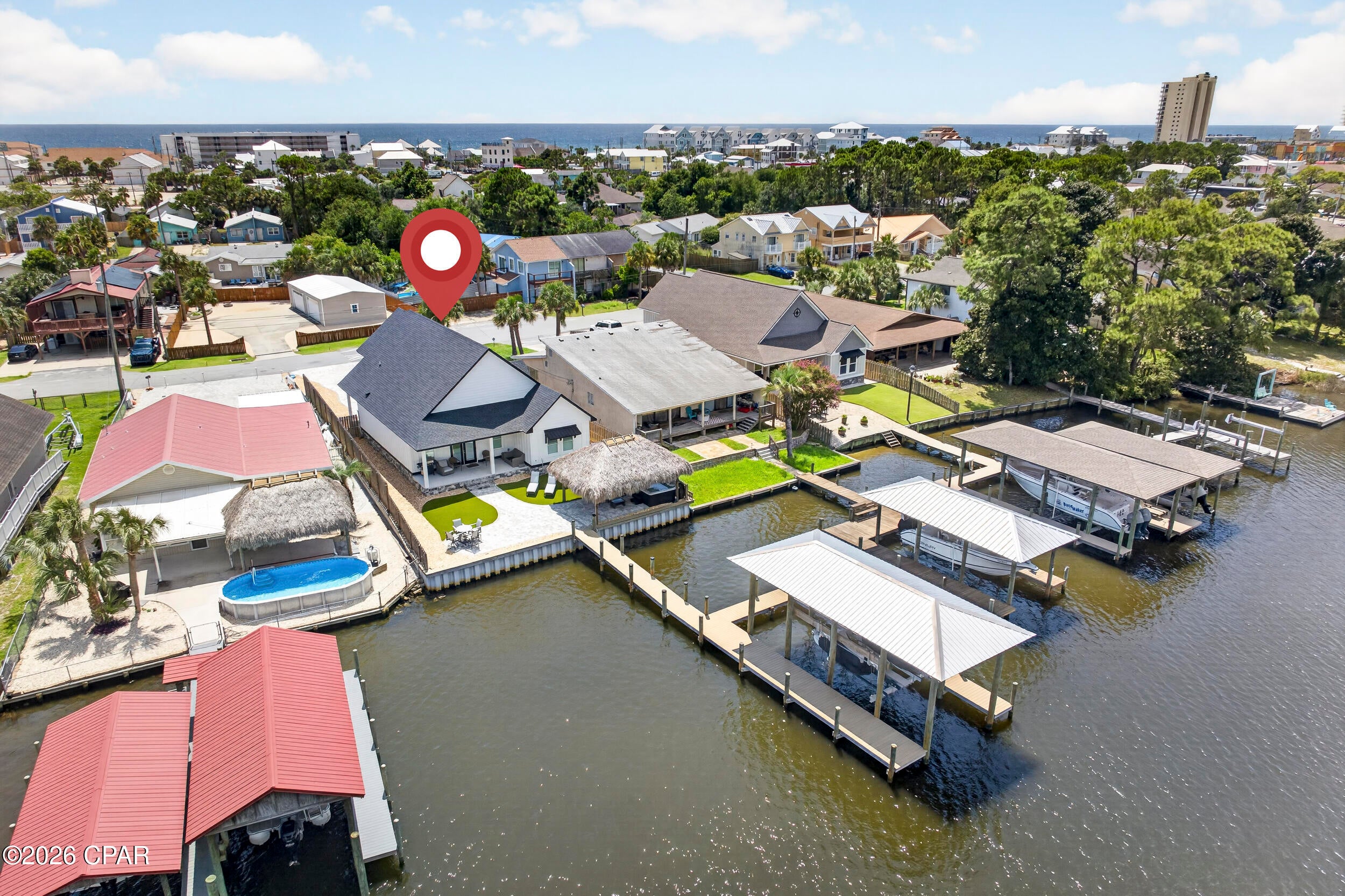 Custom-built in 2024, 8204 South Lagoon offers a rare combination in Panama City Beach: deep-water frontage, a private dock and boathouse, and a location within walking distance to the Gulf. This 4BR/3.5BA home is well suited as a primary residence or second home. The open-concept kitchen, dining, and living area creates a bright and spacious main living space, highlighted by an impressive coffered ceiling in the living room. The kitchen features custom cabinetry, granite countertops, stainless steel appliances, a large center island with seating, and a custom wood vent hood. The home features tile and LVP flooring throughout, complemented by crown molding. Three bedrooms are located on the first floor, including a large primary suite with water views. The primary bath features double vanities and a custom tiled walk-in shower. Also on the first floor is a full bathroom with a large garden tub, along with an additional half bath. Of the two first-floor guest bedrooms, one features built-in shelving, while the other offers two closets plus additional under-stair storage. On the second floor, a spacious fourth bedroom features a vaulted ceiling and its own en-suite bathroom with a tiled walk-in shower. Outside, covered front and back porches extend the living space, while a pavered driveway and walkways, synthetic grass, and rock landscaping create a finished, low-maintenance exterior.

The garage includes a separate built-out storage/tackle room for boating, fishing, and beach gear. The home also features fiber-cement siding with stone accents, impact-rated windows, and spray foam insulation.

The waterfront is where this property really stands apart. The backyard is designed to enjoy the water and includes a large waterside tiki hut with a hot tub. The property features 58 feet of seawall, an expansive dock measuring approximately 80.5' × 23.5' × 44', and a 40' × 14' boathouse with boat lift. Deep-water access makes it easy to keep your boat on the lift just steps from the house and ready whenever you are. Grand Lagoon connects with St. Andrew Bay, providing boating access to the Gulf through St. Andrews Pass.

With newer construction, deep-water boating access, low-maintenance outdoor spaces, no HOA dues, and a location within walking distance to the Gulf, 8204 South Lagoon offers a waterfront lifestyle and combination of features that is increasingly hard to find in Panama City Beach.