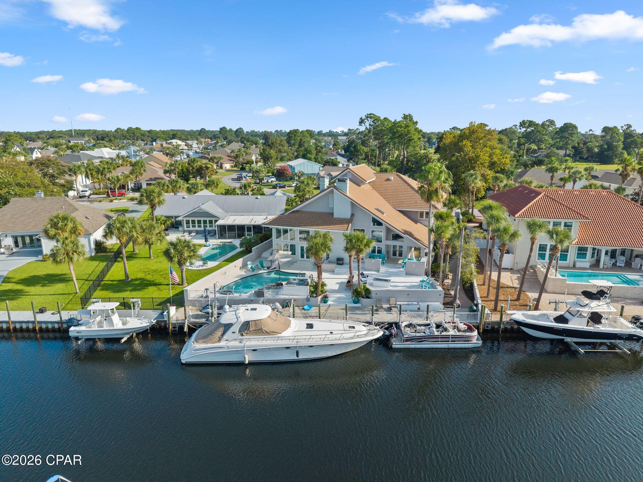 GRAND CANAL WATERFRONT LIVING IN GATED BAY POINT! Welcome to 339 Wahoo Road, a rare Panama City Beach waterfront home offering approximately 95 feet of canal frontage and an approximately 95-foot concrete dock, complete with two jet ski lifts and approximately 7 feet of water depth. Enjoy boating access to the bay and Gulf of Mexico, with Grand Lagoon, St. Andrews State Park, and Shell Island just a boat ride away. Step off the boat and into your own private waterfront retreat!

Built for entertaining, this home takes indoor-outdoor living to another level. The expansive waterfront outdoor area features a pool, hot tub, Trex deck, gas fire pit, outdoor cooking area, indoor bar, extensive indoor/outdoor bar and gathering spaces, and multiple indoor/outdoor beverage coolers--all overlooking the Grand Canal. Whether you're hosting a large celebration, cooking by the pool, gathering around the fire pit, or unwinding in the hot tub after a day on the water, this space was designed to enjoy the Florida lifestyle year-round.

Inside, custom details set this home apart, including a stunning pecky cypress and blue epoxy river knee wall, pecky cypress handrails, and an impressive marble and real-wood fireplace. Walls of windows keep the Grand Canal at the center of the home, complemented by electric living room blinds and solar-controlled bedroom shades.

The spacious kitchen features two refrigerators and a double oven, while the primary suite includes a double Jacuzzi tub. An in-law suite with a separate exterior entrance offers added flexibility for guests or multigenerational living. Additional coastal-minded features include high-impact glass, hurricane-rated doors, and a roof designed to meet applicable wind standards. The property is also located on a desirable section of the canal outside the mapped flood zone.*

Living in Bay Point means enjoying much more than the home itself. This gated Panama City Beach community offers a Jack Nicklaus-designed golf course, Bay Point Marina, waterfront restaurants and bars, and Serenity Spa. Head through the back gate and you're just minutes from the beaches, St. Andrews State Park, and Thomas Drive dining and nightlife.

Waterfront. Boating. Golf. Beaches. Entertaining. 339 Wahoo Road brings it all together. Spend the day on the Gulf, pull your boat up to your own dock, then end the evening poolside or around the fire overlooking the Grand Canal. This is Panama City Beach waterfront living at its best.

*Buyer to verify canal frontage, water depth, flood zone designation, wind/hurricane ratings, boating access, community amenities, measurements, and all information deemed important.
