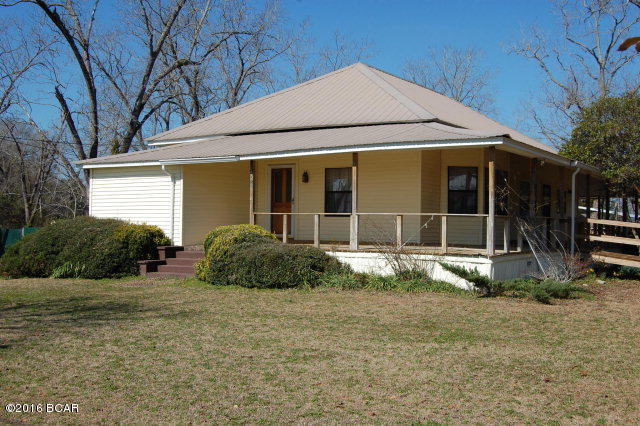 Charming older farm house type home with wrap around porch located east of Greenwood on Fort Road/Hwy 69. 3BR 2 1/2 Bth on over half acre. Large shop and two metal carports included. Home has been updated including walk in glass shower, laminate floors, paneling, vinyl siding, metal roof and built in storage. Large rooms and high ceilings Home is situated on partially fenced 1/2 acre with lots of fruit trees including pear and mass producing fig!