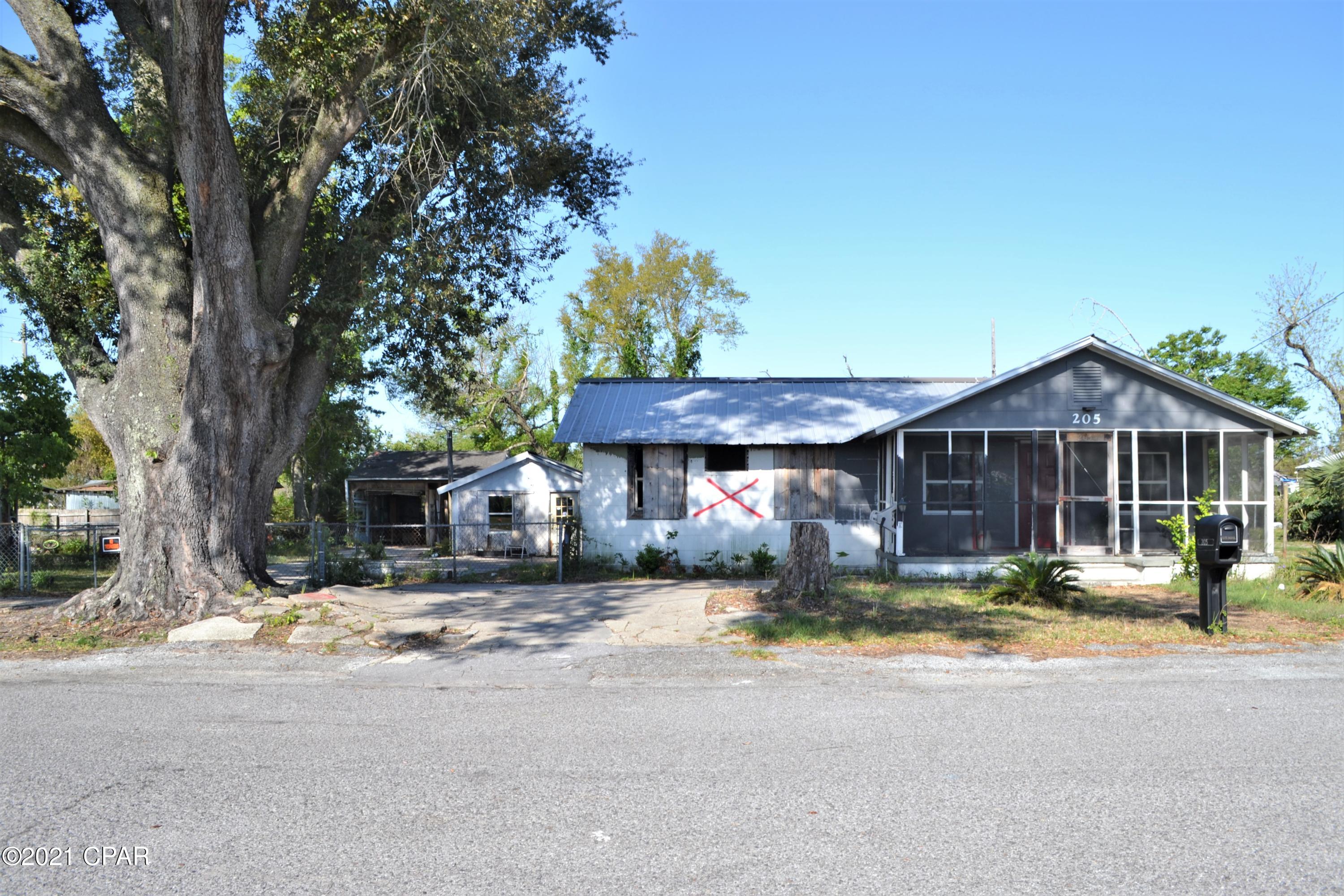 INVESTMENT OPPORTUNITY!  This 100x140 lot is mostly fenced and has an older hurricane damaged home (home cleared of possessions and roof replaced after the storm), a 16x36 workshop, an RV height 2 bay carport, and a 10x14 screened gazebo.  All structures need work to restore.  Other options would be to demo the home and rebuild or a manufactured home is allowed per the city (please call city for more details).  Public water and sewer are available.  This property is located near shopping, restaurants, schools and other amenities.  Call today for an appointment.
