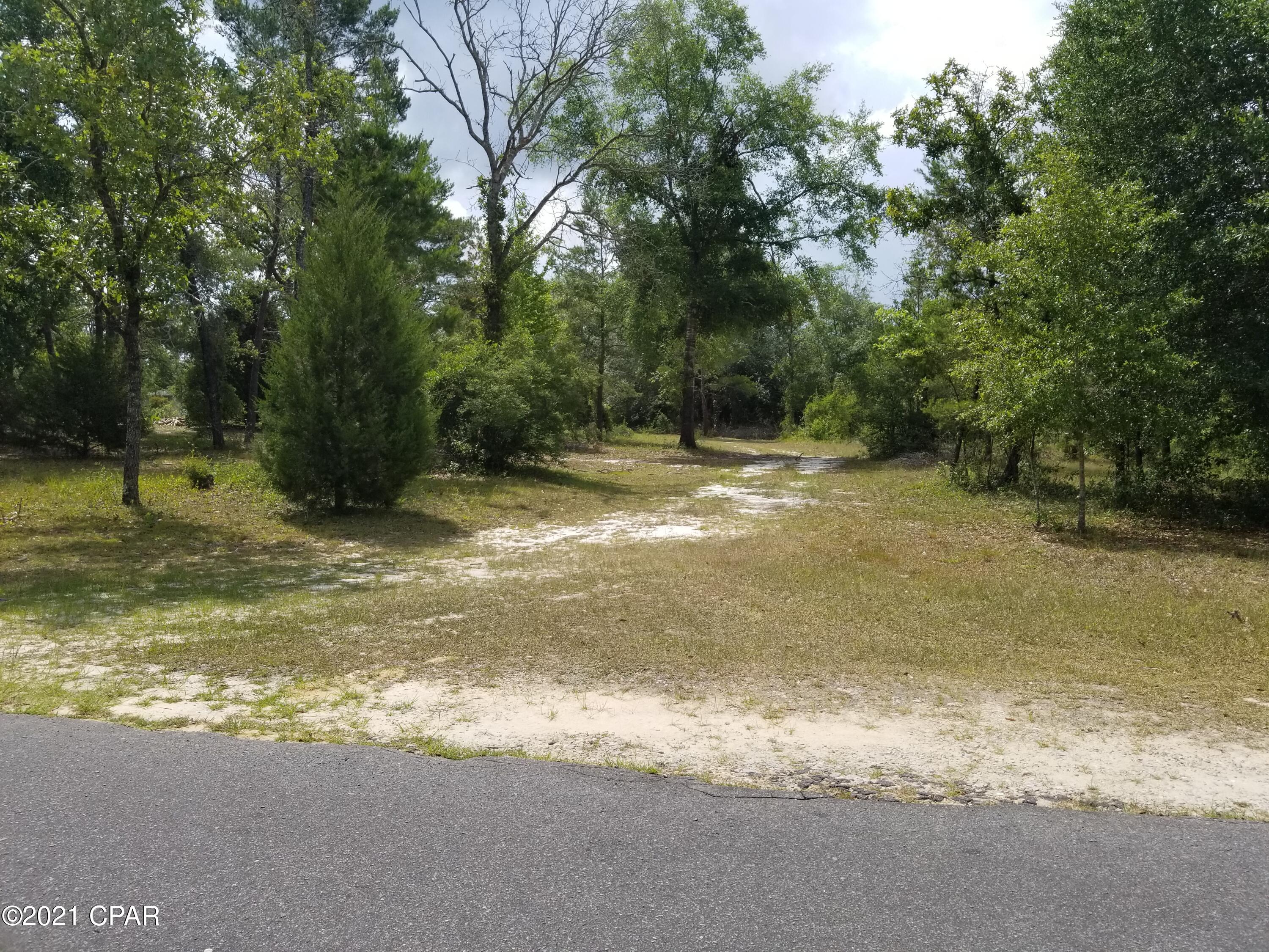 Horses welcome! The huge lot at 5 (+/-) flat acres is one of the largest in the security gated subdivision of Leisure Lakes. Already partially cleared, this flat lot was a former home site so it has a circle drive way, septic tank and field lines. The lot also has a view of the large, clear freshwater lake. The lake is about a mile across, or about 3 miles around. Bring your kayaks or boats and go exploring. In addition, there is a 20x26 steel building with 2 rollup doors, and a 12x24 storage building. There is plenty of room for horses or trail riding. The property backs up to a wildlife preserve surrounded by a 10-foot tall fence. There is an easement thar runs around the entire subdivision on properties on the outside perimeter.  Subdivision amenities include basketball court, tennis court, boat launch, fishing, swimming pool, covered pavilion, men's and women's restrooms and more. Only 30 minutes from Panama City, 25 minutes to Chipley, and 45 minutes to the World's Most Beautiful Beaches. Live security guards are on duty weekdays, and each resident has a unique code for entry. In addition, there is a second lake that is about half the size of the big lake and also is spring fed. This would be a great family homestead or bugout property. Be sure and see all of the photos.