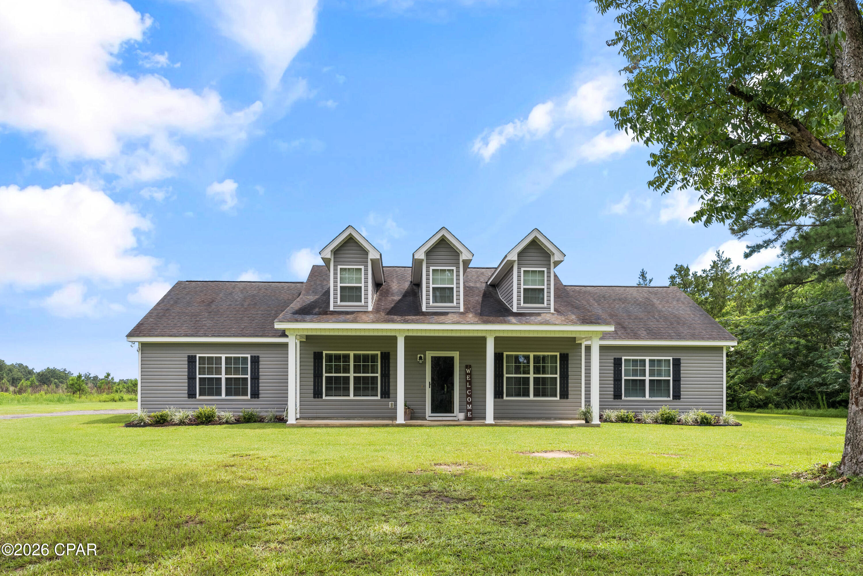 Discover the perfect blend of modern comfort and peaceful country living in this beautifully maintained 4-bedroom, 3-bath home offering 2,348 sq ft of living space on 2.31 mostly cleared acres. Built in 2016, this home features an open floor plan, stainless steel appliances, soft-close cabinets, and a spacious primary suite with two walk-in closets. Enjoy relaxing mornings on the covered front porch or evenings on the expansive covered back porch. The property includes a 1,336 sq ft detached 3-car garage/workshop with RV hookup, providing exceptional space for vehicles, equipment, hobbies, and storage. Conveniently located near Falling Waters State Park with easy access to I-10, Panama City Beach, and Dothan. No HOA and plenty of room to enjoy the privacy and flexibility of country living.