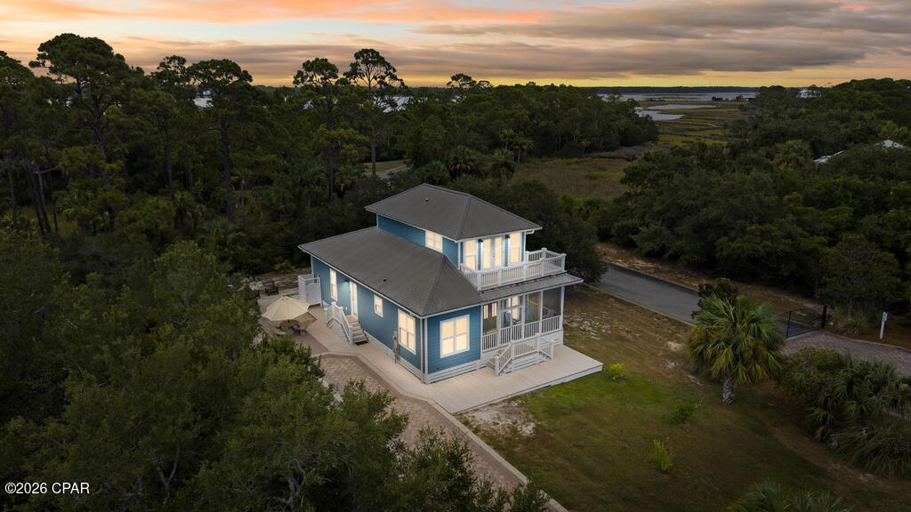 Discover the laid-back charm of Old Florida in beautiful Indian Pass! Nestled in the peaceful and picturesque Mystic Palms subdivision, this 3-bedroom, 2-bath beach cottage offers the perfect combination of coastal comfort, natural beauty, and easy access to the Gulf. The property feels private and serene while offering the amenities that make beach living so enjoyable. Residents of Mystic Palms have access to a dedicated community beach and swimming pool, with secured access for added convenience. The beautiful paver driveway creates an inviting approach to this coastal retreat, surrounded by native pines, palms, and lush landscaping. A spacious screened porch spans the front of the home and is the perfect place to enjoy your morning coffee or unwind after a day at the beach. Step inside and you're greeted by a spacious living area featuring beautiful hardwood floors that create a warm, inviting feel. To the left, the kitchen and dining area flow seamlessly into the living space. The kitchen is beautifully appointed with gorgeous cabinetry, stainless steel appliances, granite countertops, and a breakfast bar that creates a natural connection between the kitchen and living room. The laundry room is conveniently located on the main level. Two generously sized guest bedrooms are also located downstairs, each offering ample closet space. One bedroom provides direct access to the screened porch, creating a wonderful private retreat. A full bathroom completes the first floor. Upstairs, the private primary suite offers a peaceful escape, with the beautiful hardwood flooring continuing throughout. French doors open to a private balcony where you can enjoy the surrounding natural setting and the peaceful atmosphere of Indian Pass. The spacious primary bathroom features a relaxing garden tub, separate shower, and large walk-in closet. Outside, there's even more to love. An outdoor shower makes rinsing off after a day at the beach easy, while the spacious driveway provides plenty of parking for family and guests, with room for your boat as well. Indian Pass is Old Florida at its finest--quiet, natural, uncrowded, and wonderfully peaceful, yet close enough to enjoy the area's restaurants, boating, fishing, and other coastal attractions. Whether you're looking for a full-time residence, a vacation getaway, or an investment property, this home offers the opportunity to experience the authentic, relaxed lifestyle that makes Indian Pass so special. Come slow down, breathe in the Gulf air, and discover your own piece of Old Florida.