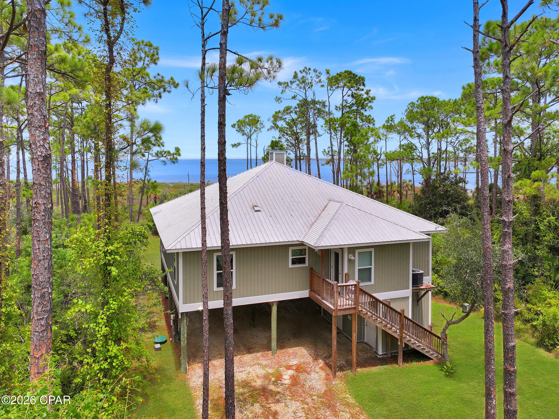 CURRENTLY UNDER CONTRACT, SELLER WILL CONSIDER BACKUP OFFERS - - - Looking for Bay front living with Privacy and a feel of Seclusion? This home is where breathtaking sunsets, endless water views, and the laid-back Forgotten Coast lifestyle come together. This 3-bedroom, 2-bath home offers an inviting open floor plan, creating the perfect space for gathering with family and friends. The spacious living area flows seamlessly into the kitchen and is highlighted by a cozy wood-burning fireplace, making it just as enjoyable on cool coastal evenings as it is during sunny beach days. Luxury vinyl plank flooring runs throughout the home for easy maintenance and coastal durability. The spacious primary suite features a large walk-in closet conveniently located off the ensuite bathroom, providing plenty of storage. Step outside to the fully screened bayfront deck, where you can relax while overlooking the sparkling waters of St. Joseph Bay. From the deck, a private path leads directly to the shoreline, making it easy to launch a kayak, paddleboard, fish, or simply enjoy the peaceful beauty of the bay. The ground level is designed with convenience in mind, featuring an outdoor shower, insulated storage area for all your beach and water gear, and an elevator shaft that has already been pre-wired for future installation. Located just a short drive from Port St. Joe, you'll enjoy easy access to local restaurants, shopping, and live music, while the nearby Loggerhead Run Bike Path offers miles of scenic walking, running, and biking along Cape San Blas. Whether you're searching for a full-time residence, vacation getaway, or investment opportunity, this bayfront home is your chance to experience one of Florida's most treasured coastal destinations.