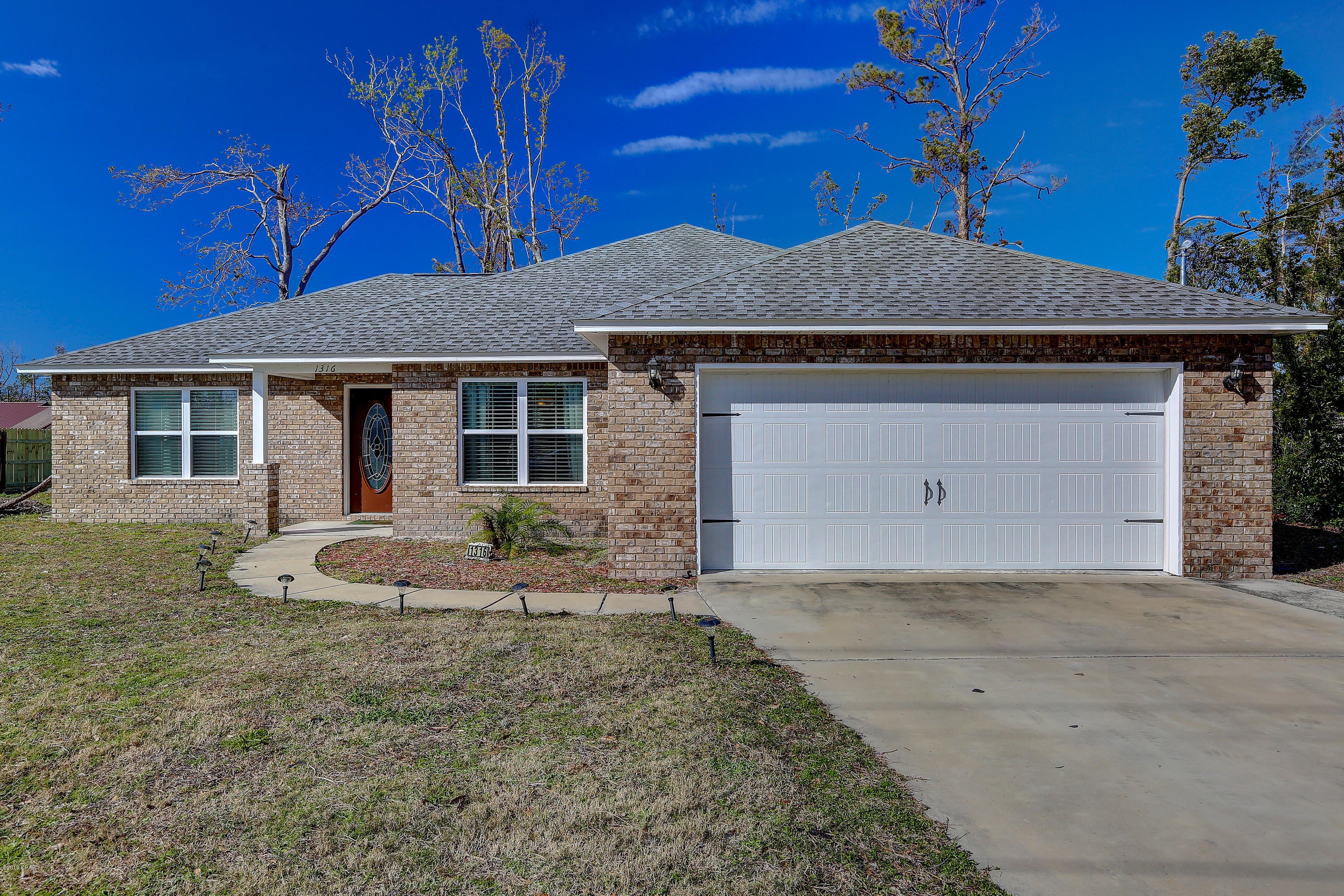 This Lynn Haven 3 bed 2 bath split plan home is 1,534 sf and offers a kitchen with breakfast nook, stainless appliances and breakfast bar, formal dining room and a large living room with cathedral ceiling.  The master has an en-suite bathroom with walk in shower, soaking tub, double vanities and walk in closet.  There is also a walk in pantry and laundry room. Outside there is a covered patio and large yard.  The hurricane destroyed the fence as well as uprooted trees whose stumps still remain.