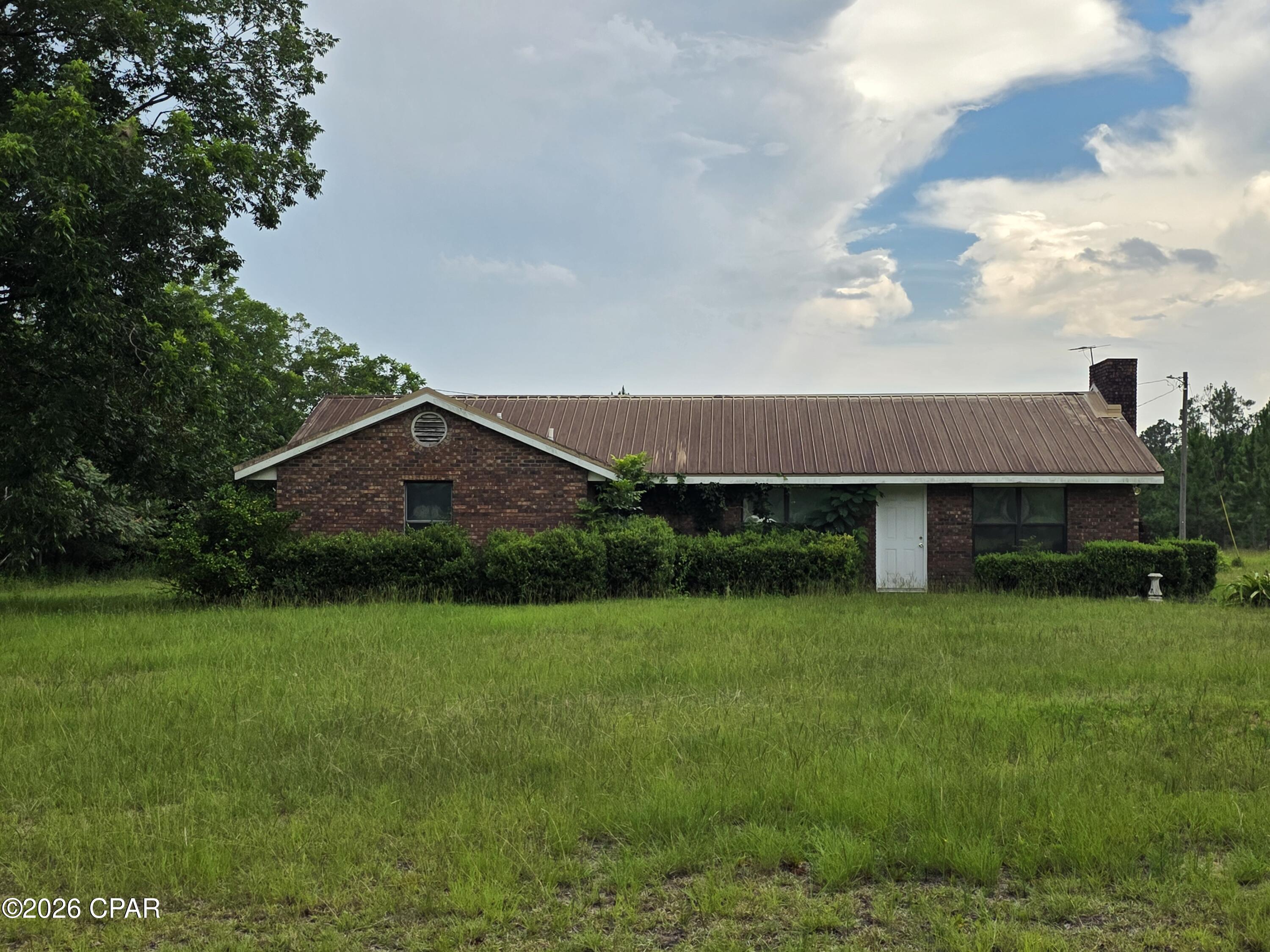 Quiet country living with this 3/2 brick home on 12.5 +/- acres and is private and not seen from the road. Home offers an open floorplan with kitchen, dining, and living room.  Wood burning fireplace. Down the hall you will find 3 spacious bedrooms and bonus room that could be an office or additional storage. Large utility room. Screened in back porch. Large workshop. Property is a mix of cleared and wooded land. Not far from Alford to the west and Marianna to the east.