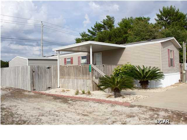 This, well maintained, 2004 mobile home is just a few blocks from the Gulf on PCB Parkway. It already has Commercial Zoning in place which would allow for a wonderful home office. Or how about a nice, low maintenance get-a-way spot where you can drive your golf cart for a beautiful sunset on Laguna Beach.  This property would also make a great vacation rental. You will enjoy sitting on the covered front porch with your early morning cup of coffee or relax in the very private, large backyard, perfect for a backyard BBQ and entertaining. There is even a shower to rinse off after your day on the beach. The home has 2 nice sized bedrooms, a large open floor plan in your main living area and a huge walk in closet in the master bedroom.