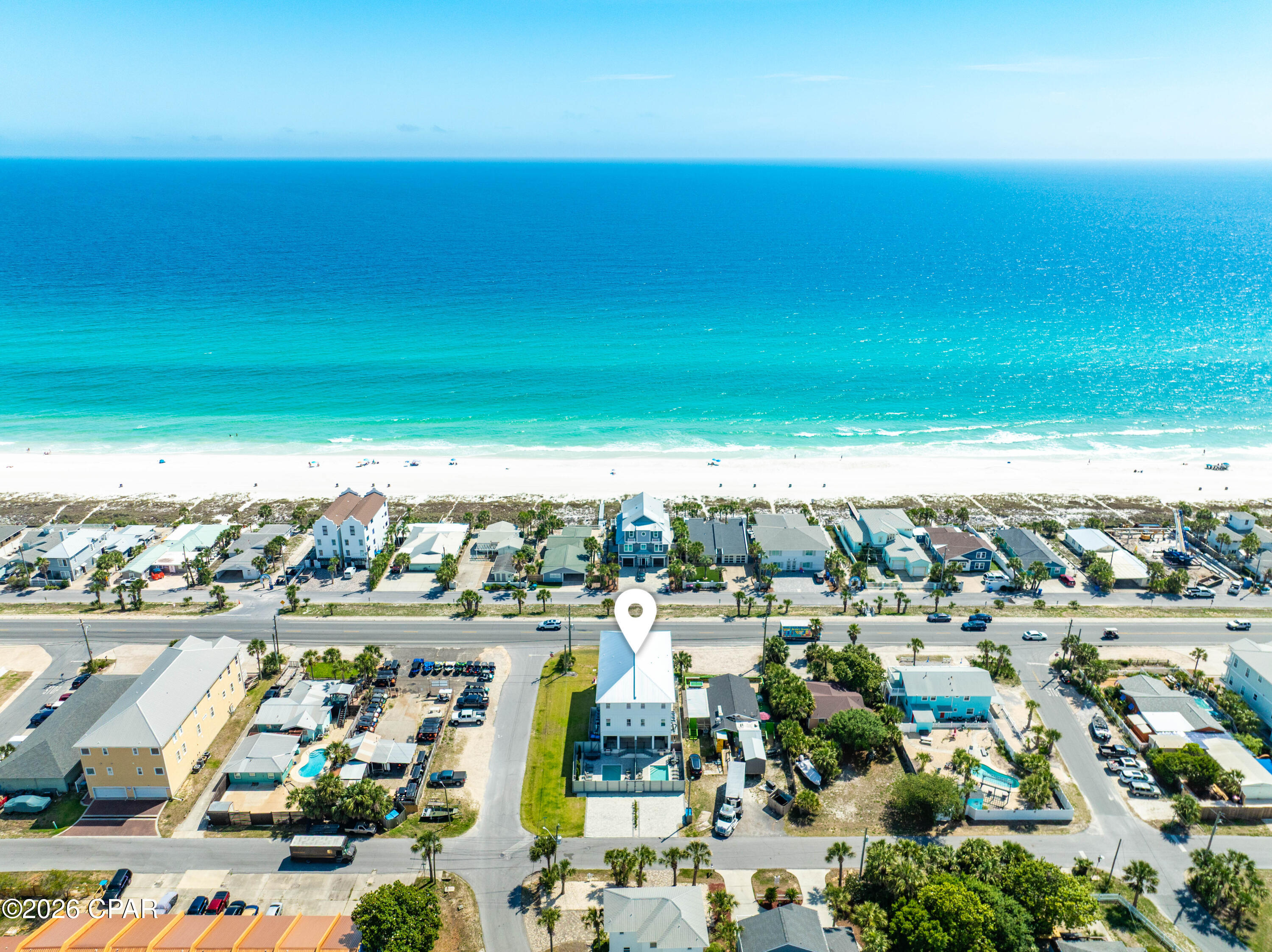One of just two attached townhomes on Front Beach Road in Panama City Beach, this newly built three-story residence is offered fully furnished and turnkey, living entirely on its own -- a private entrance, a private fenced pool, and dedicated paver parking. It stands directly across Front Beach Road from the sugar-white sand and emerald Gulf, with two public beach accesses only a short walk away. Gulf views open from the main living level and the top-floor primary suite, and a private elevator serves all three floors. The living level is anchored by a designer kitchen -- white shaker cabinetry, a quartz waterfall peninsula, premium stainless appliances, and a statement tile backsplash -- flowing into a generous dining area and a Gulf-view balcony made for sunset. One floor down, a dedicated game room with a pool table, air hockey, foosball, and a wet bar opens to the backyard, where a private pool and paver sun deck sit alongside an outdoor kitchen and grill. Upstairs, the third-floor primary is a private retreat: a king suite with its own Gulf-view balcony, a spa-inspired bath in marble-look tile, a dual vanity, and a walk-in closet. Bedrooms on every level -- several with two beds, plus a children's bunk room -- welcome large groups with ease. Just minutes from M.B. Miller Pier, Pier Park, and Topgolf -- a standout primary home, second residence, or Gulf-view investment in Panama City Beach.

Set over three floors with nine-foot ceilings and wide-plank wood-look flooring, the layout keeps a full level of living between the entry and the bedrooms above.
On the ground floor, the recreation room opens to the fenced backyard and is served by a full bath, while a guest bedroom with ensuite bath, a spacious home office, and a second laundry room finish the level.
The middle floor gathers the open kitchen, dining, and living, with two more bedrooms and a powder bath positioned for guests.
The uppermost floor belongs to the primary suite, alongside two additional bedrooms, a full laundry room, and a wet bar just outside the suite.
By the pool, lounge seating and alfresco dining complete the fenced deck, and dedicated parking holds four vehicles.