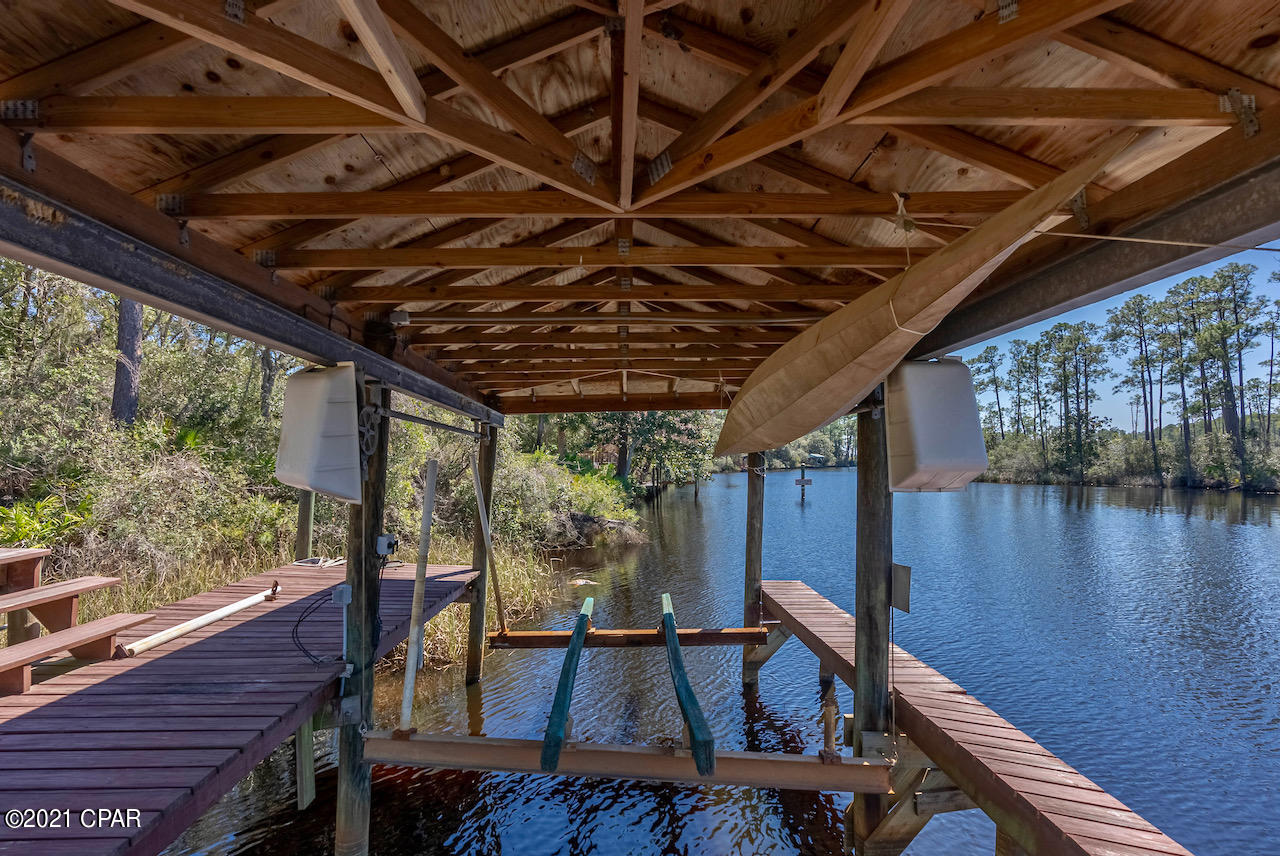 Paradise awaits you in  this luxurious creekfront home with dock and boat lift!  Two private lots w/1.45 acres of gulf access waterfrontage, and facing Highway 388W. Beach, stores, and city offices  are less than 15 min. away.  Build another home,, or possibly use for home based business.  No HOA!!!  There are only a few homes that can keep their boats in the water overnight with their own private boat house and this is one of them. Across the creek from Rivercamps, but without the restrictions.  Enter through your private gate with large area for parking, carport ,and RV port.  Rare find, act fast! Lots of glass adorns the home with

double glass door in kitchen/dining area and

floor to ceiling windows in the living room,

overlooking the large screen room and nice

oaks in the natural landscaping. Large living room, awesome kitchen with stainless steel appliances, wine cooler, island with sink and dishwasher and the vinyl plank floors add to the gorgeous upgrades in this home. Split bedroom plan.  The master suite features a double vanity and large walk in shower and closet.  The guest bath has a large vanity, shower, toilet room, and walk in closet.  Lots and lots of cabinets and closets.  This home has recessed lighting in the living room and kitchen.  The screen porch is very spacious with  Jacuzzi that will convey. Have your coffee in the Jacuzzi and watch the boats go by!   There is also a fire pit with a swing!  With the new
highway going to the airport these homes will have a less busy service road.  Pier Park and Lattitude Margaritaville are close.  This property is a wonderful investment!  Please verify all information.