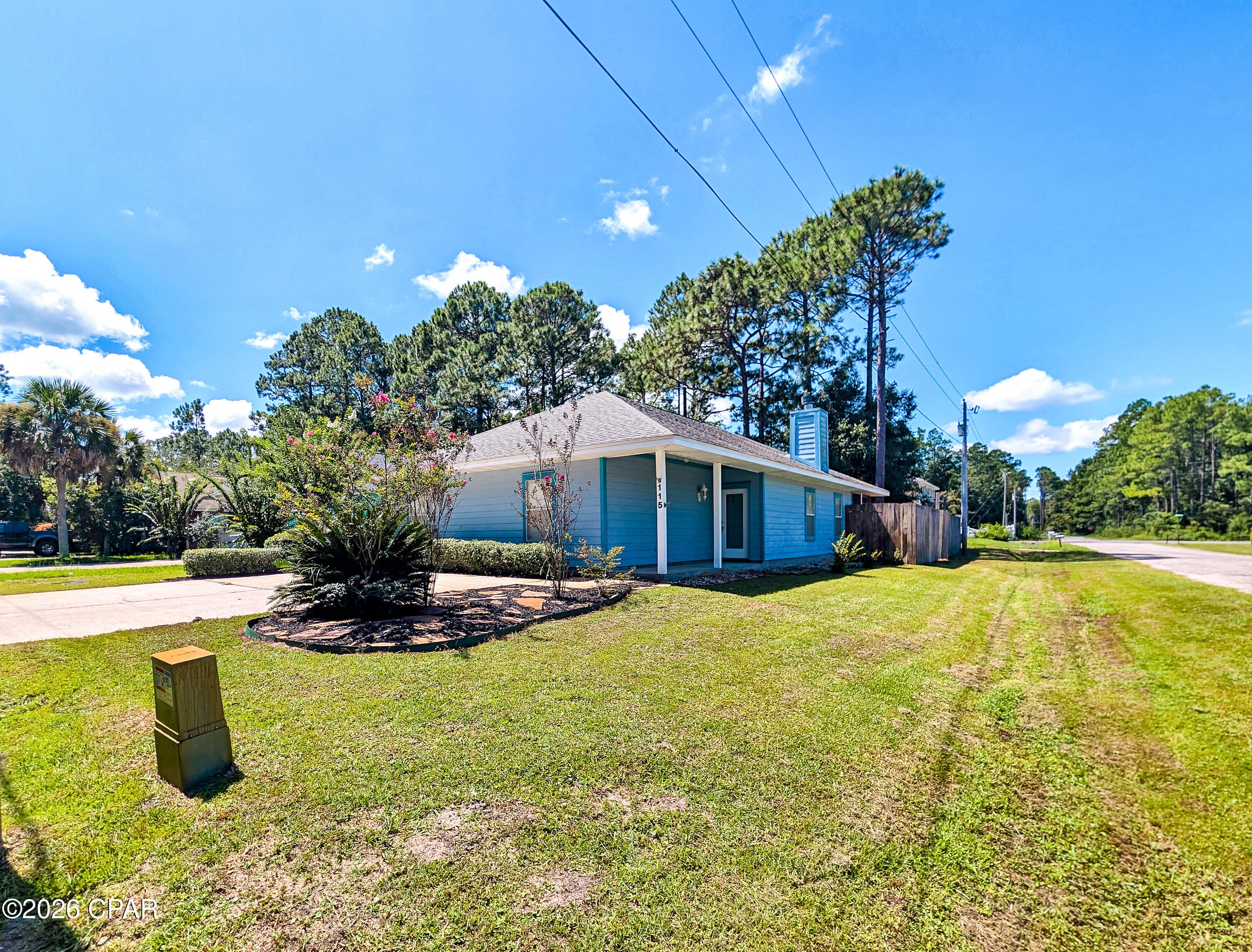 Some houses you tour. This one you settle into.

It starts on the corner lot, under longleaf pines and oaks that throw real shade by late afternoon -- the kind that makes the back yard usable in August. Behind the full fence there's a fire pit, a garden, stone and gravel walkways, crape myrtle and palm, all of it kept green by full irrigation off a well pump. Come through the double gate on E Russel Ave and there's room to park the boat, the RV, whatever you tow.

Inside, 1,610 square feet of open-concept living under wood floors, with a wood-burning fireplace for the three weeks a year the Panhandle earns one. Craftsman moldings in 6'' and 4'' run throughout -- the detail you notice on the second walkthrough, not the first. The kitchen keeps light shaker cabinets, granite counters and a breakfast bar built for morning conversation, with the laundry room just off it. Three bedrooms, three full baths, every bedroom with its own -- no one negotiates for the shower. Travertine floors and surrounds throughout, with a walk-in travertine shower and jetted tub in the primary.

Evenings belong to the screened back porch that runs nearly the full width of the back of home.

Town of Santa Rosa puts you minutes from shopping, dining and schools, under two miles from the Choctawhatchee Bay boat launch, and ten minutes from Emerald Coast sand!