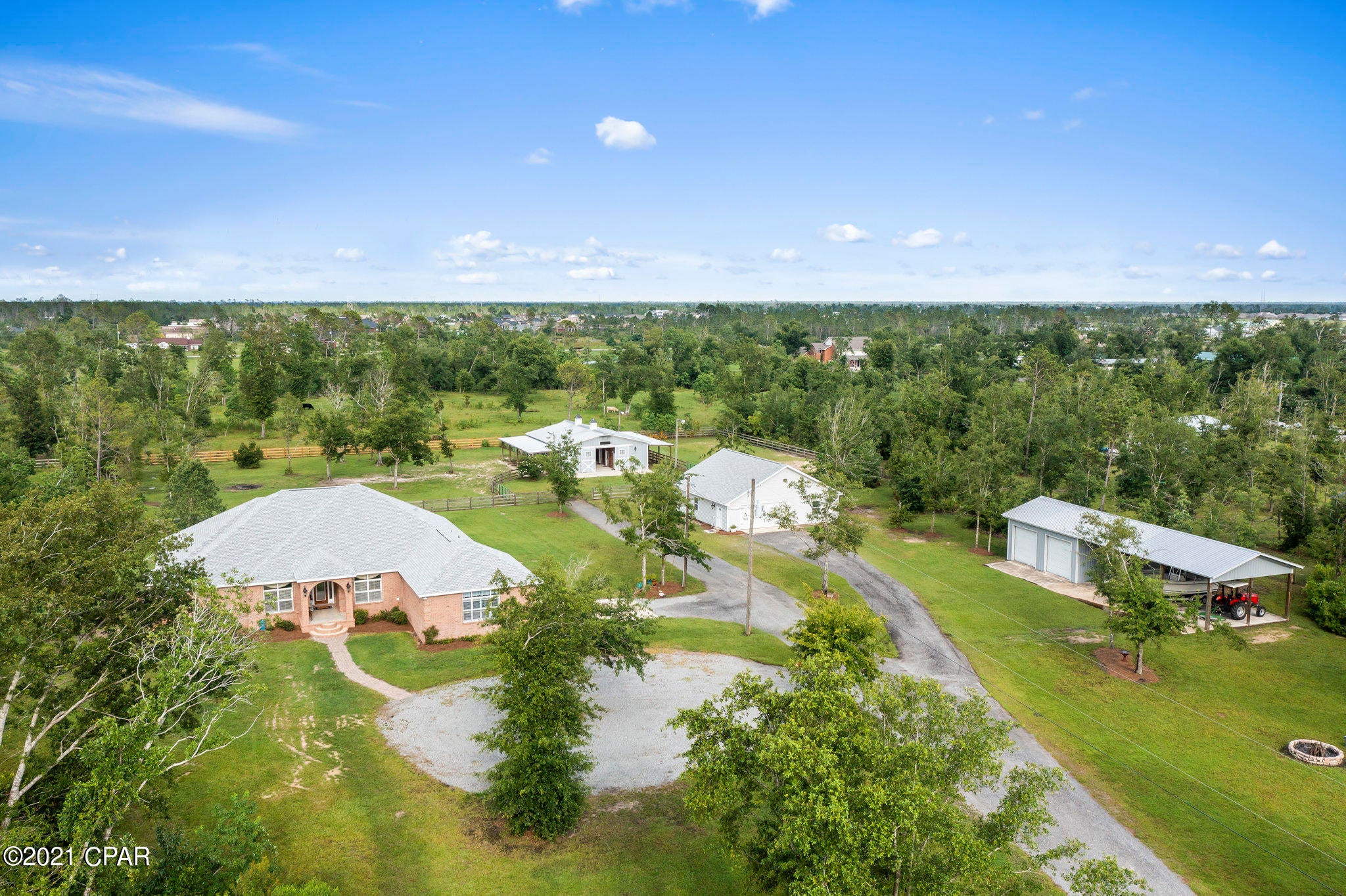 Country living close to town and beaches: drive through the lighted brick columns with large black gates to your oasis -  4 bedroom/3 full bath all brick custom home with inground fiberglass pool and spa on 5.54 acres. Cathedral ceilings in great room with gas fireplace. Transom windows throughout home allow for lots of natural light.  Home has two master bedrooms both with french doors leading to the pool deck, the largest being a split plan with ensuite and two walk in closets. Master bath has granite counters with dual sinks, solid oak custom cabinets, double walk in shower, jetted large tub, and separate makeup vanity. The second master has a walk-in closet and ensuite bathroom with granite countertops, custom solid oak cabinets, dual sinks, tub/shower combo along with french doors to the pool deck. The 1600 sq ft workshop is plumbed for a bathroom, has a double car garage, side door entry, and new architectural shingle roof. The workshop could be a mother-in-law home or recreational room. The custom 5 stall horse barn has Priefert stall fronts each with hay and feeding doors, indoor wash bay with hot water heater, separate tack room, and separate feed room. Each stall has custom dutch doors. There is also a lighted arena for riding. Trailer and boat covered storage with three open bays and two enclosed bays with roll up doors for storage. Kitchen is equipped with solid oak custom cabinets, granite counters, stainless steel new appliances. Indoor large laundry room also has custom solid oak cabinets and granite counters. Third bath has custom cabinet with granite counters, large shower and opens to the pool deck. Custom plantation shutters and crown molding throughout this lovely home along with new architectural shingle roof, new HVAC and new flooring. Kinetico water system and 2 hot water heaters. New well tank. Open floor plan allowing for a great entertaining space and large great room wired for surround sound. Covered lanai across back of home with granite bar overlooking inground pool and spa. The property features a pond with a rock design waterfall and is located at the end of a dead end road backing up to over 2000 wooded acres. An additional 3+acres adjoining the property is available for purchase for a total of 8.4 acres. Only 15 minute drive to downtown and less than 1 mile to the Deerpoint boat ramp. Be in fresh or salt water in a jiffy. Don't miss out on this lovely estate.