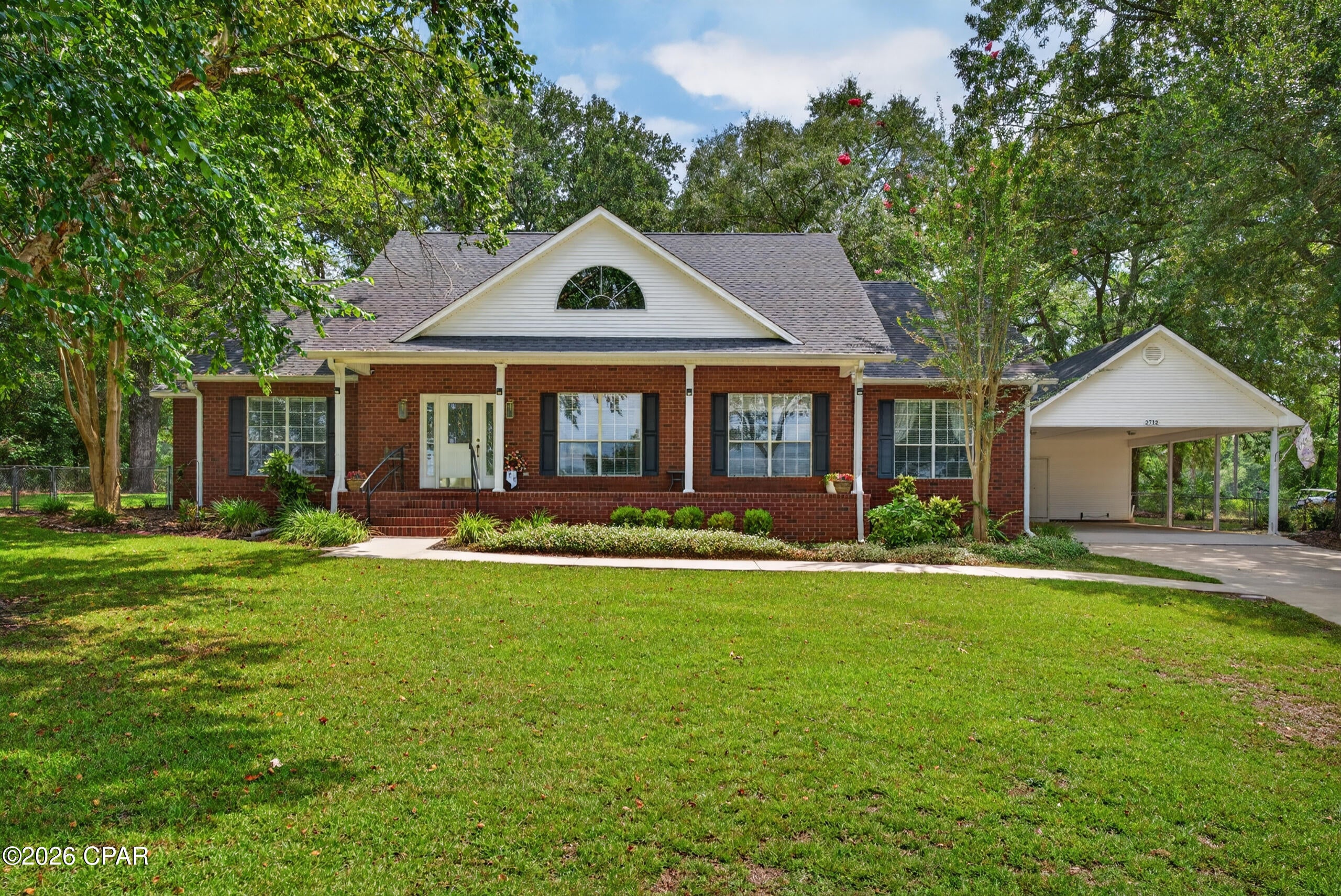 Enjoy peaceful living in the desirable Dogwood Lakes Golf Community at 2712 Marian Drive in Bonifay. Known for its scenic lakes, golf course views, mature trees, and quiet streets, this established community offers a relaxed setting with plenty of natural beauty. Situated on a spacious 0.7-acre lot with no HOA, the property overlooks the lake and golf course while a canopy of shade trees provides added privacy from the first fairway.

This well-maintained brick home offers approximately 2,203 heated and cooled square feet, with more than 2,700 square feet under roof. The welcoming foyer opens into a spacious living room featuring vaulted ceilings and a wood-burning fireplace. Double doors lead to a bright Florida room surrounded by windows, creating the perfect place to unwind while enjoying views of the yard and surrounding landscape.

The kitchen includes wood cabinetry, solid-surface countertops, built-in appliances, wall oven, microwave, and an eat-in bar overlooking the dining area. An additional room offers flexibility for a home office, den, hobby room, or formal dining space.

The spacious primary suite features a double vanity, walk-in shower, separate jetted tub, and walk-in closet. Two additional bedrooms share a convenient Jack-and-Jill-style bathroom, while a half bath near the foyer is ideal for guests.

Outside, the fenced backyard, deck, oversized double carport, and attached enclosed workshop provide abundant space for entertaining, hobbies, storage, and outdoor enjoyment. There is also room to add a pool, garden, or additional workspace. Recent improvements include updates to the roof, water heater, deck, and more.

With tranquil lake views, golf course scenery, no HOA, and the charm of the Dogwood Lakes community, this property offers a wonderful opportunity to enjoy a relaxed Florida lifestyle.