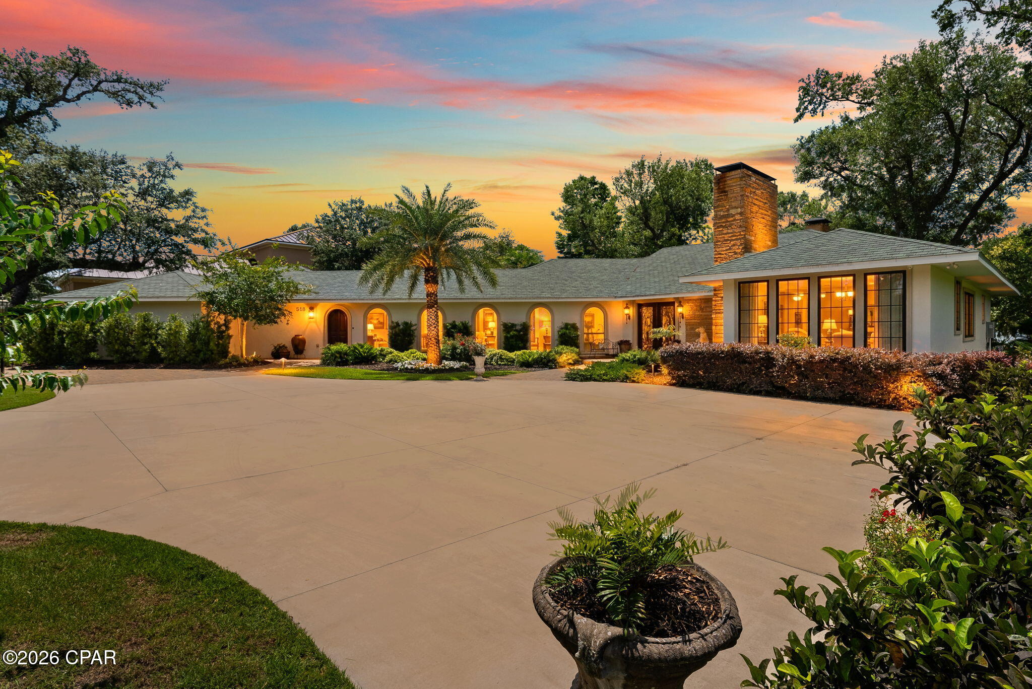 Experience timeless elegance and waterfront serenity in this extraordinary Mediterranean-inspired estate, perfectly positioned on a sprawling bayfront lot. From the moment you arrive, the home's graceful arches, warm architectural details, and inviting courtyard create an unforgettable first impression, setting the stage for a lifestyle defined by beauty, comfort, and coastal charm.
Inside, the residence unfolds with refined sophistication. A spacious living room anchored by a stunning fireplace opens to breathtaking bay views, creating the perfect setting for both relaxed evenings and elegant entertaining. The formal dining room showcases exquisite custom plaster-finished walls, offering a rich and artistic backdrop for memorable gatherings. At the heart of the home, the chef's kitchen is as functional as it is beautiful, featuring a striking brick accent wall, double ovens, a gas range, and an oversized island with a butcher block top. Sunlit and inviting, the eat-in kitchen overlooks both the tranquil koi pond and the sparkling bay beyond, seamlessly blending indoor and outdoor living. Just off the kitchen, a cozy sitting room with its own fireplace provides the perfect retreat for quiet mornings or intimate conversations.
The thoughtfully designed split floor plan offers privacy and comfort, highlighted by a luxurious master suite that includes a rare original 1940 greenhouse feature, adding a touch of history and charm. The spa-like master bathroom invites relaxation with a large soaking tub, separate shower, and an expansive walk-in closet. Three additional bedrooms, each with their own full bathrooms, ensure comfort for family and guests alike, with one guest suite featuring its own fireplace for added warmth and character. A gallery-style hallway runs through the home, offering the perfect space to display art and personal collections.
Outdoors, the property transforms into a true private oasis. Multiple water features, including a beautifully stocked koi pond, create a peaceful, resort-like atmosphere. The custom covered patio and pergola with an outdoor fireplace and built-in grilling area make entertaining effortless, while the expansive lawn stretches to the water's edge, complete with a seawall and direct bay access. Adding a sense of fun and uniqueness, the grounds also feature a zip line and a custom playhouse, making this estate as playful as it is luxurious.
Blending classic Mediterranean architecture with modern comforts and unparalleled waterfront living, this one-of-a-kind property offers a lifestyle that is both elegant and unforgettable. Whether enjoying quiet sunsets over the bay or hosting gatherings under the stars, this home is a rare opportunity to own a true coastal masterpiece.