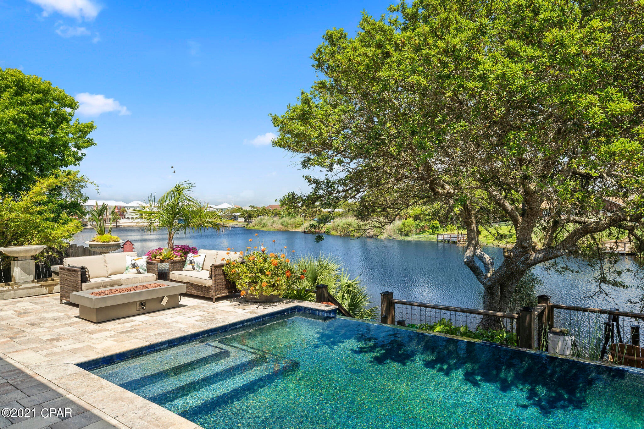 Resort living in Panama City Beach. You will be amazed at the views of your infinity pool overlooking the lake. This one-of-a-kind property was totally renovated in 2018. Entertain your family and friends in your infinity pool, enjoy the breeze sitting on your front or back porch, watch the sunset over the lake from your dock, or spend some time kayaking on the lake.  Just a short stroll or golf cart ride to the sugar white sands and emerald gulf waters. This 3 bedroom 3 bath home is perfect to be your dream home, second home, or vacation rental.  Step through the double entry doors to find an open floorplan with tile floors, high ceilings, archways, and stunning light fixtures. The Living area is bright and open overlooking the pool, deck, and lake. The modern and fully equipped kitchen is ideal for preparing a delicious dinner or having a quick snack at the island. The Kitchen features custom cabinets, granite countertops, and stainless appliances. The large master bedroom includes access to the pool and lake, closet with custom shelving and custom ensuite spa like bath with double sink vanity and walk in tiled shower.  One of the two additional bedrooms includes a custom ensuite bath. The additional bedroom and bathroom have also been updated with custom features. 2 car garage with built in storage, Gracious porches adorn both the front and back of the home overlooking the pristine landscaping making this your private oasis within walking distance of the beach.  All measurements are approximate and should be verified by buyer if important.