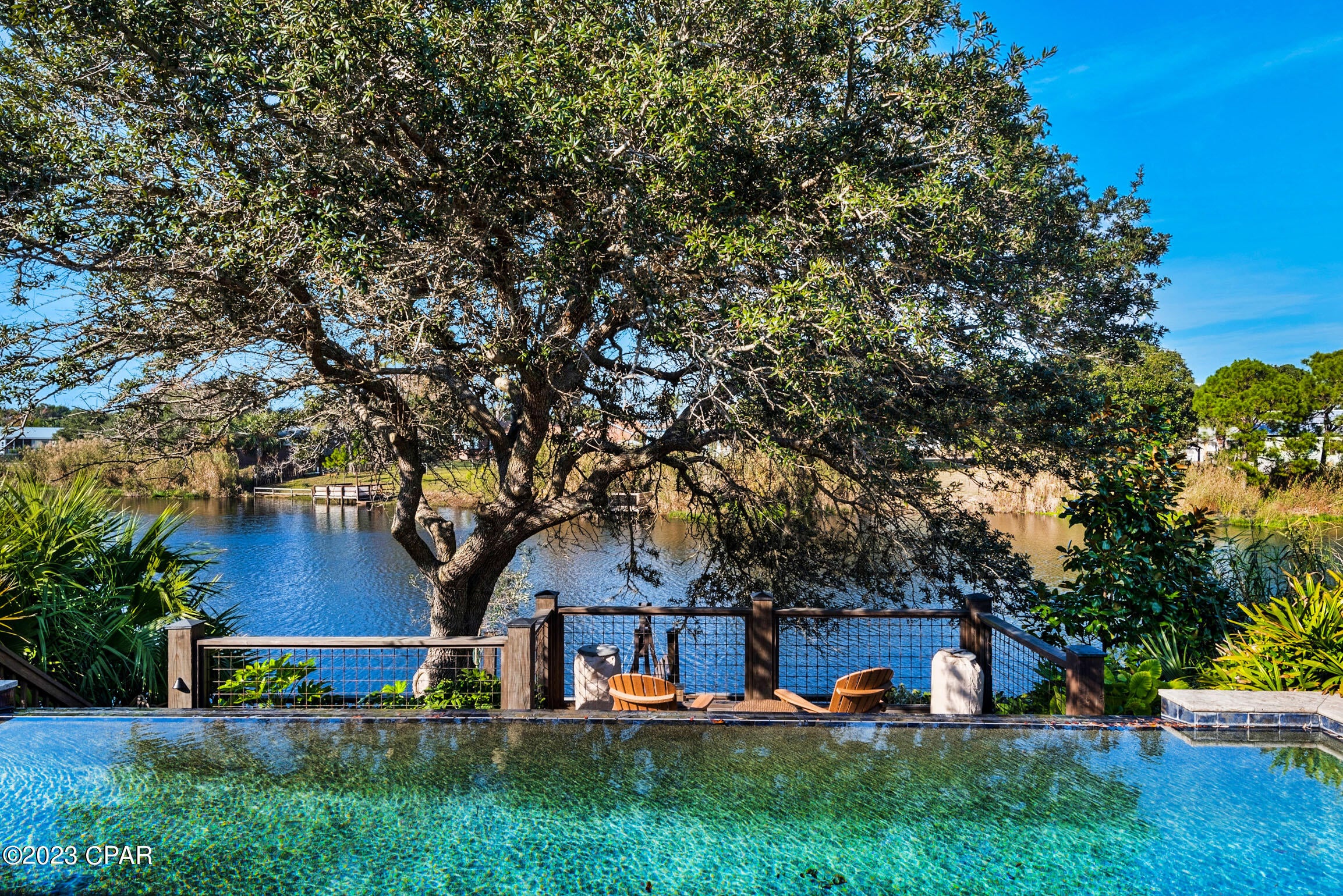 Under Contract! SELLER ACCEPTING BACKUP OFFERS! Welcome to this stunningly remodeled 3 bedroom, 3 bath house in the highly sought-after location of Panama City Beach. A Short Term/VRBO Rental Machine! This property boasts a private infinity pool and is situated on the serene lake, offering breathtaking panoramic views that your friends, family and vacationing guests will NEVER forget! As you step inside, you'll be greeted by an open-concept living space that is perfect for entertaining guests and relaxing with family. The living room is bright and airy, with large windows + swinging French doors that flood the home with natural light. The modern kitchen features sleek stainless steel appliances, granite countertops, white storybook cabinetry, a kitchen island + so much more! Relax in the infinity pool that can be lit at night, your private lake dock, or the porches.
The beautifully landscaped outdoor living is the highlight of this amazing getaway, providing multi-level settings for you to take in the stunning WATERFRONT lifestyle. Bring along a kayak to enjoy peaceful time spent on the lake. Enjoy the gulf water breezes from either of the spacious front or back porches. Your new beach home is just steps away from the gorgeous beaches of Panama City Beach! Just minutes down the road you'll find all that PCB and 30A has to offer. You're also just 5 miles to Rosemary Beach! 2 Car garage and very large driveway....so invite everyone over and make memories!