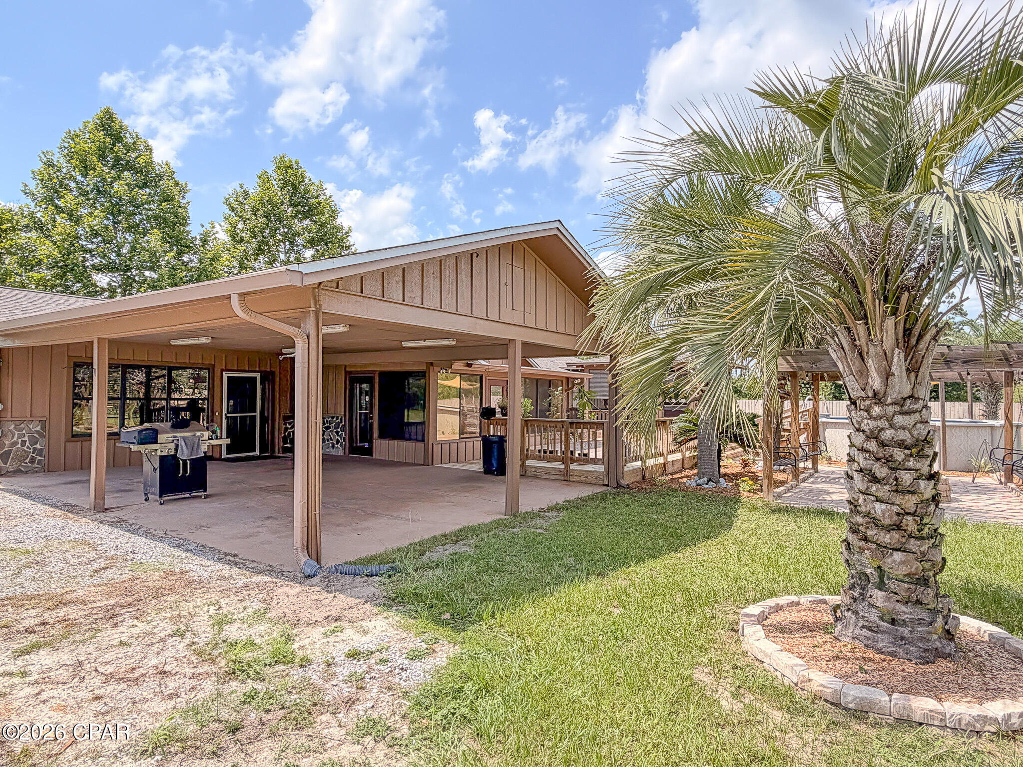 Welcome to your own private country retreat, where peaceful living meets modern convenience. Nestled on 1.184 acres, this spacious 3-bedroom, 2-bath home offers over 2,500 square feet of thoughtfully designed living space, just 30 minutes from the sugar-white sands and emerald waters of Panama City Beach.

Step inside to an inviting open-concept layout featuring soaring vaulted ceilings that span the kitchen, dining, and living areas. The kitchen is beautifully appointed with granite countertops, creating the perfect gathering space for family and friends. The impressive 14' x 22' living room is anchored by a stunning floor-to-ceiling stone fireplace, while the expansive 21' x 22' den with custom built-in shelving provides endless possibilities for entertaining, relaxing, or working from home.

Enjoy year-round sunshine in the 20' x 10' Florida sunroom overlooking your backyard oasis. Outside, you'll find an above-ground pool, a covered screened porch complete with a whirlpool spa, and a charming pergola that creates the perfect setting for outdoor entertaining or quiet evenings under the stars. Beyond the backyard, take in serene views of a small pond with access to a private dock.

The primary suite and guest bath both feature double-sink vanities, while the generous 6' x 10' laundry room offers plenty of workspace along with peaceful outdoor views.

Constructed with beautiful stone and rough-cut cedar siding, this home exudes timeless character and curb appeal. Additional features include two outbuildings for abundant storage, an oversized carport, and a gated driveway with an electric entrance for added privacy and security.

If you've been searching for the tranquility of country living without sacrificing access to shopping, dining, and the Gulf Coast's world-famous beaches, this exceptional property truly offers the best of both worlds.