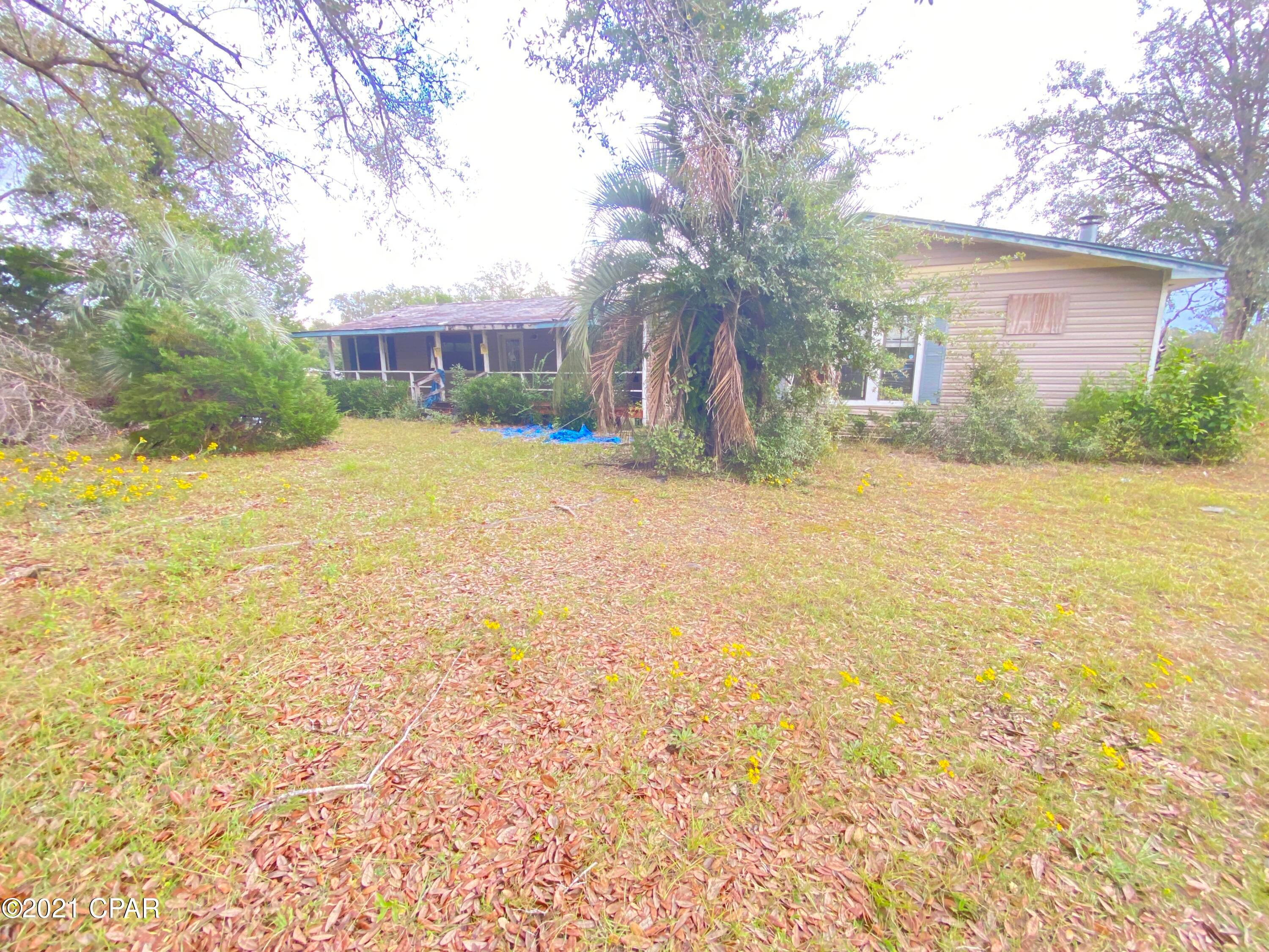 Large home hurricane impacted with large storage building complete with 4 stalls for workshop and storage. This property is situated on over an acre there is a long driveway, double carport and large covered back porch.
