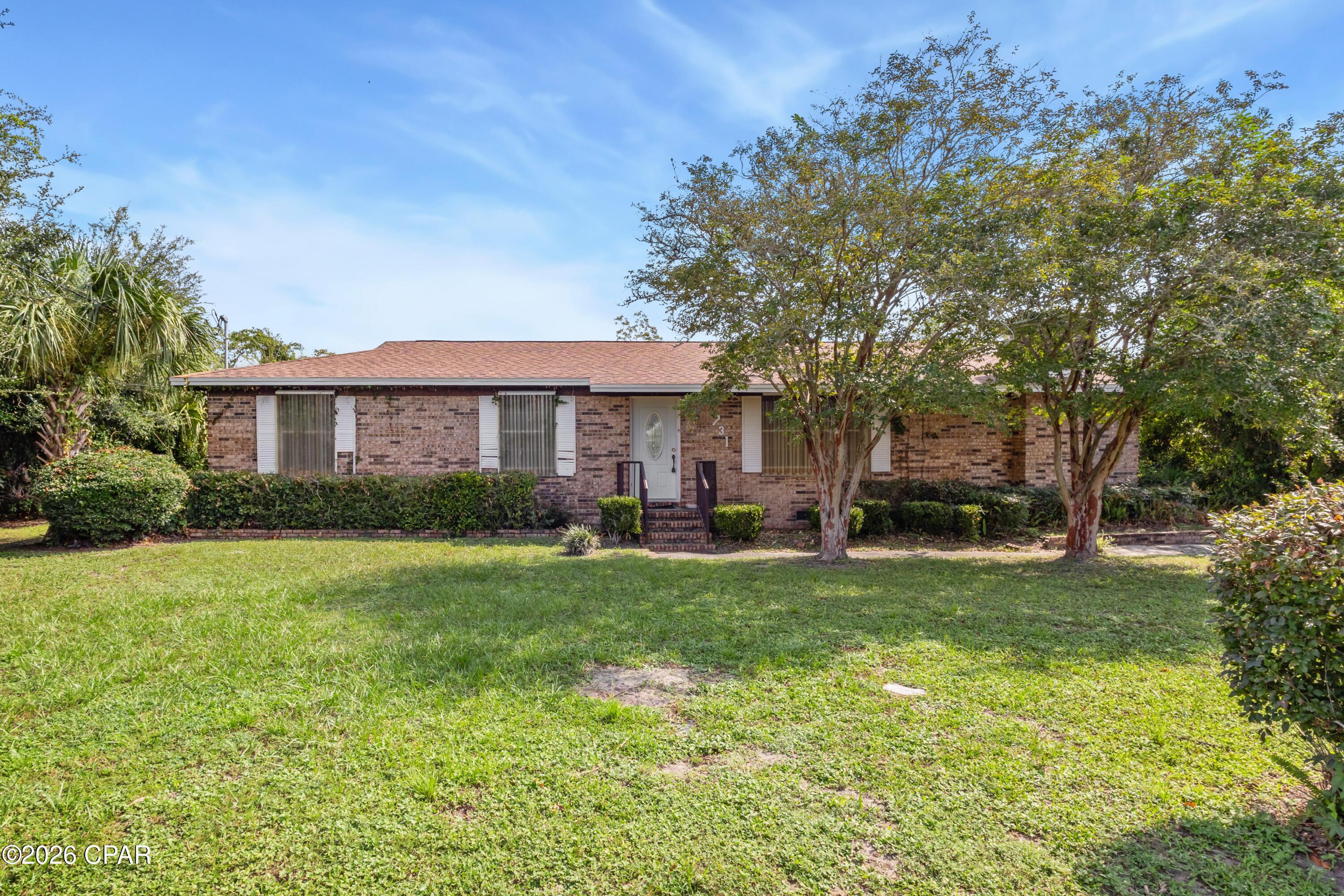 Welcome to this 3-bedroom, 2-bath brick home situated on a spacious 100x150 lot surrounded by mature trees. Inside, the home offers room to spread out with both a living room and a separate family room featuring a fireplace. Just off the family room is an interior laundry area with additional storage space, providing added potential for renovation and customization. The large kitchen has ample counter and cabinet space, white appliances, and plenty of room for everyday meals and gatherings.  Offering lots of potential, this home is ready for a new owner to bring their vision to life with updates and personal touches along the way. Outside, the huge backyard provides plenty of room for relaxing, entertaining, pets, play, or creating an outdoor retreat to enjoy year-round. The convenient location puts you near Tyndall Air Force Base, a public boat ramp, parks, schools, restaurants, shopping, and other everyday conveniences. With its spacious lot, mature trees, multiple living areas, and room to make it your own, this home is ready for its next chapter. Call today to schedule your private preview!