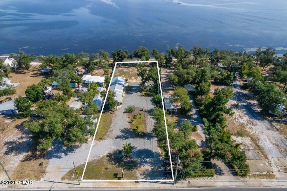 Enjoy exceptional waterfront living on this stunning .75-acre property featuring 90 feet of beautiful East Bay shoreline in the heart of Bay County, Florida. Privacy fencing offers the perfect retreat to take in the views, while a newer sprinkler system keeps your garden creations maintained. This property offers an unbeatable lifestyle location. Sidewalks provide easy access to two nearby parks, including a public pier, walking trails, a large wooded playground, and a Frisbee golf course--all within walking distance. Directly across the street, enjoy a wide variety of restaurants, cafes, bakeries, coffee shops, and diverse dining options, including Thai, sushi, Italian, and more. Nearby is a full-service marina that offers charter fishing excursions, waterfront dining, a tiki bar, and social gathering opportunities, creating endless recreational possibilities right outside your door.
Zoned Mixed-Use, this property presents incredible opportunities beyond personal enjoyment. Whether you envision a private waterfront retreat, short-term rental investment, multifamily development, townhomes, apartments, or up to 12 units, the development potential is substantial. Its prime frontage along Tyndall Parkway, with thousands of daily passing vehicles, also makes it an outstanding candidate for retail, hospitality, restaurant, or other commercial opportunities. Rarely does a property combine waterfront beauty, walkable amenities, flexible mixed-use zoning, and exceptional development potential in one offering. Whether you're seeking a dream home, income-producing investment, or large-scale development opportunity, this East Bay property delivers endless possibilities. Don't miss this rare chance to own one of Bay County's most versatile waterfront properties. Contact your favorite Realtor today to schedule a private showing or learn more. 
The Studio Apartment/oversized double garage holds no value unless the Buyer builds a primary dwelling.
Some photos have been modified by AI. Buyer to verify any information deemed important.