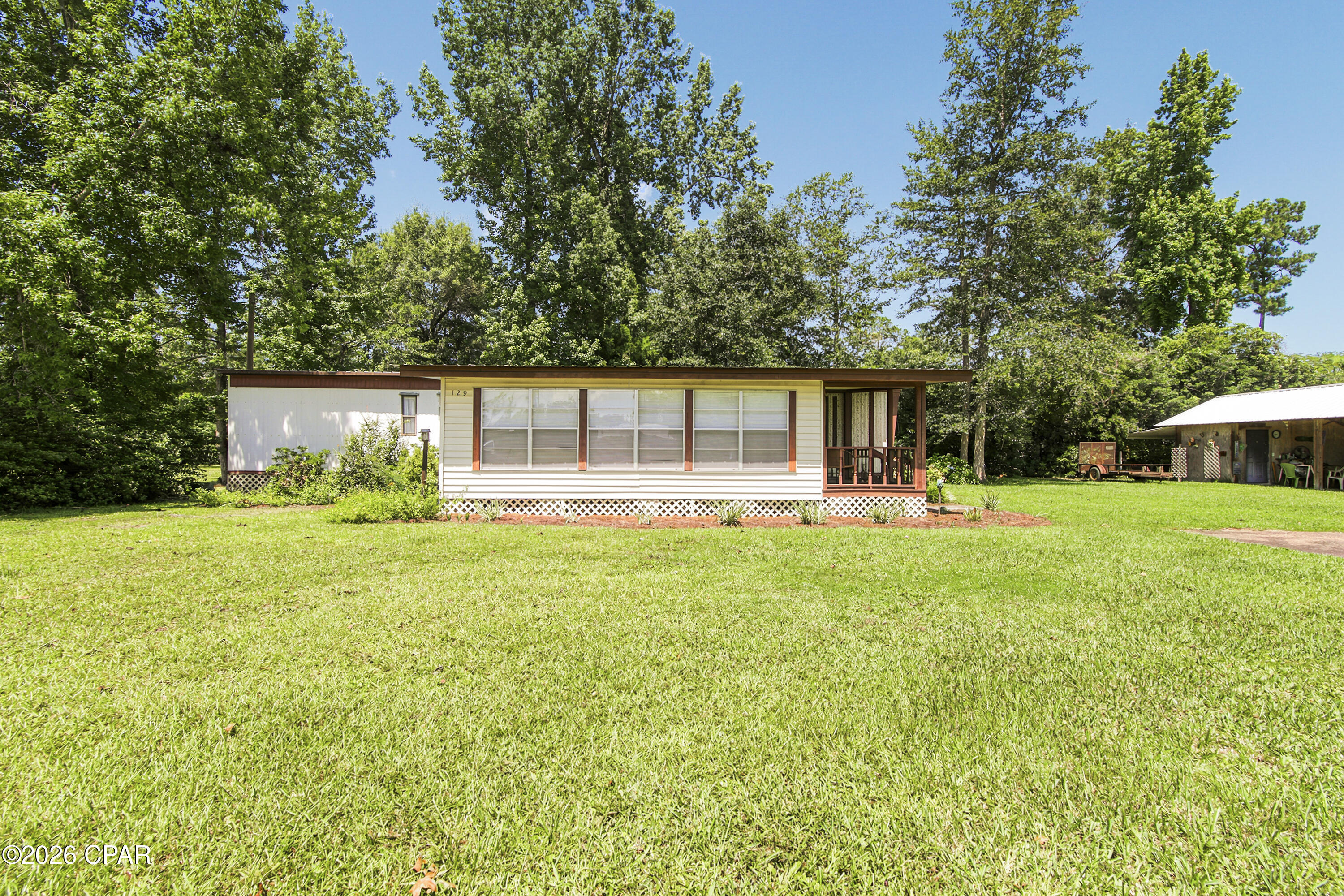 Move right into this immaculately maintained 1980 mobile home situated on a spacious lot in the heart of Wewahitchka! This well-cared-for home features updated flooring, a welcoming back porch, and a large heated and cooled sunroom that provides additional year-round living space. Whether you're looking for a full-time residence, weekend getaway, or the perfect fish camp, this property is ready to enjoy from day one. Outside, you'll find a pole barn with a covered fish cleaning station and power to charge your boat, making it ideal for anglers and outdoor enthusiasts. A private well and septic system service the home, and all furnishings and contents, excluding personal items, will convey, offering a truly turnkey opportunity. Located approximately 5 miles from the Dead Lakes County Park Boat Ramp, you'll have quick access to some of North Florida's best fishing and boating. Plus, you're only about 20 miles from Port St. Joe, where you can enjoy beautiful Gulf beaches, restaurants, shopping, and entertainment. Buyer should verify all measurements and information deemed important.