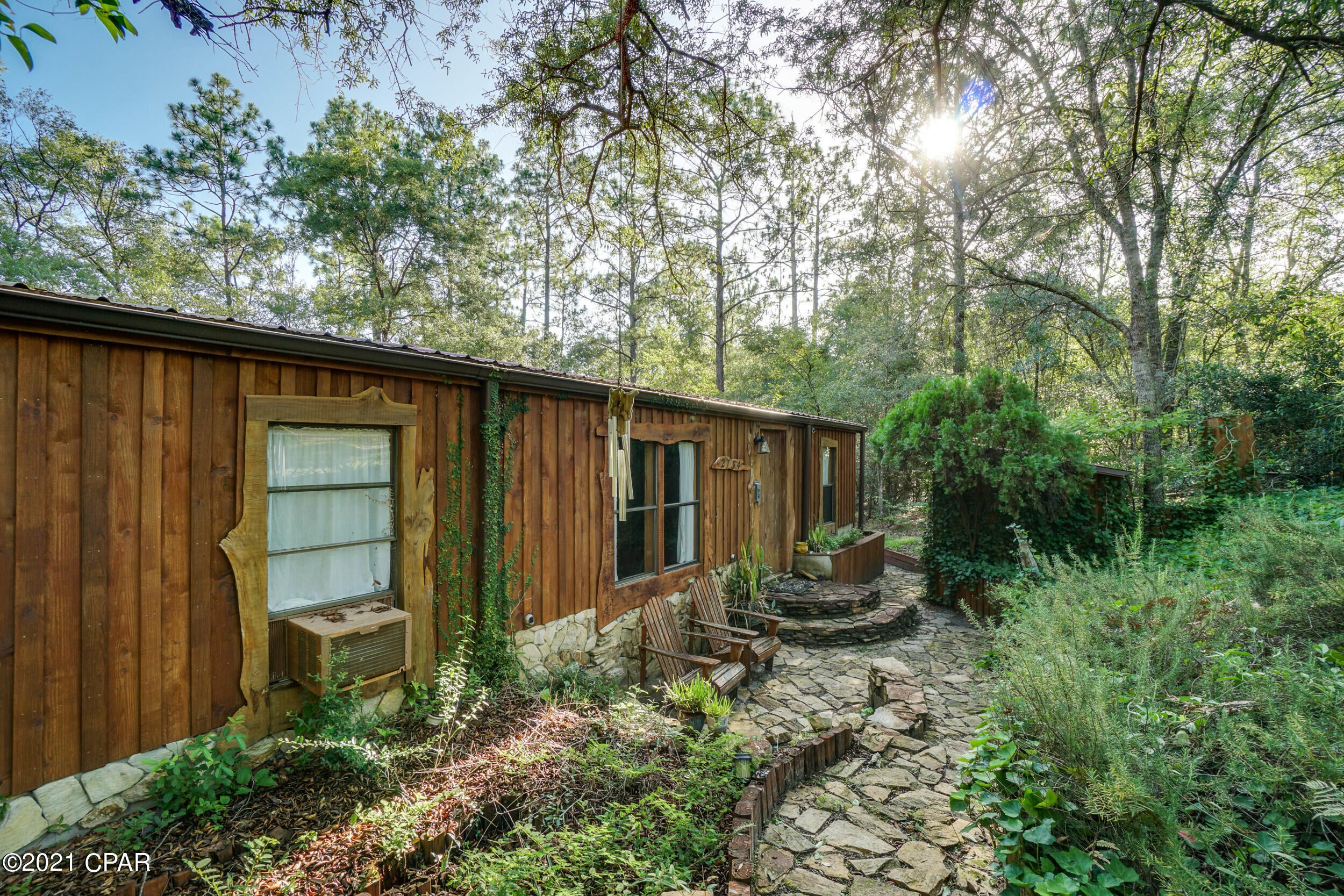 *BACK ON THE MARKET* Fully furnished, rustic, lakeside retreat on just under one acre. Secluded, but convenient to Hwy 77 only 30 minutes to either Panama City or Chipley. The home has a cabin-like feel with cedar clad walls inside and out, with live edge trim and natural stone accents.  There is a large open living area and kitchen featuring lighted open shelving and extra deep lower cabinets.  A beautiful glass door invites you onto the screened porch that encompasses the entire back of the home so you can fully enjoy the lake view. There is a small flex room that can be used as an office, studio, playroom, or even a small bedroom/bunkroom.  The home also includes two full baths, washer/dryer hook-ups, and ample storage.  There is additional storage under the house, another small shed and a covered firewood storage area. The exterior boasts a wellhouse with additional storage and terraced planting beds to satisfy all your gardening needs. There is even an outdoor cooking / entertaining area! Previously used as a vacation home, the greenhouse, dock, boathouse and grounds need some full time attention and repairs to return this artfully designed property to its full potential. All information deemed to be accurate.  Buyer to verify if important