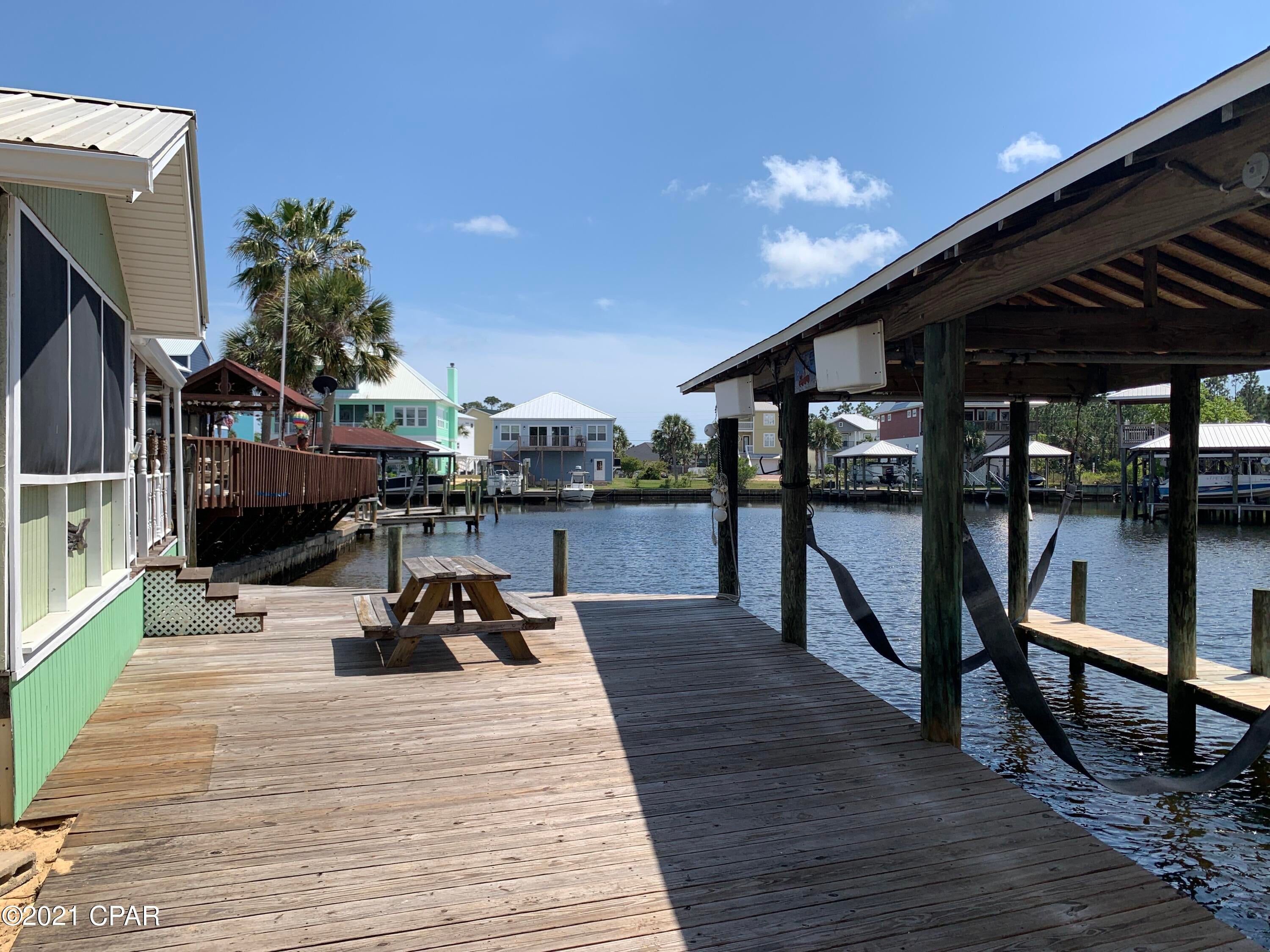 Enjoy the cool breeze coming off the water while you drop your boat in, and head to the gulf in this waterfront  home. We have direct Gulf access through the canal and deep water. This is a boater's dream. When you come home, you can lift the boat into it's very own boathouse with brand new decking and enjoy the oversized dock built in April of 2018. The RJ Gorman seawall and dock is 45ft wide, and at it's longest 18.5ft adding bounds of usable space. Inside the dark stained hardwood floors have been well cared for, not to mention the durable tile in the entryway. There's plenty of storage in the home, and an additional shed in the front. You cannot find this kind of water access, and boat accommodations at a better price than this!