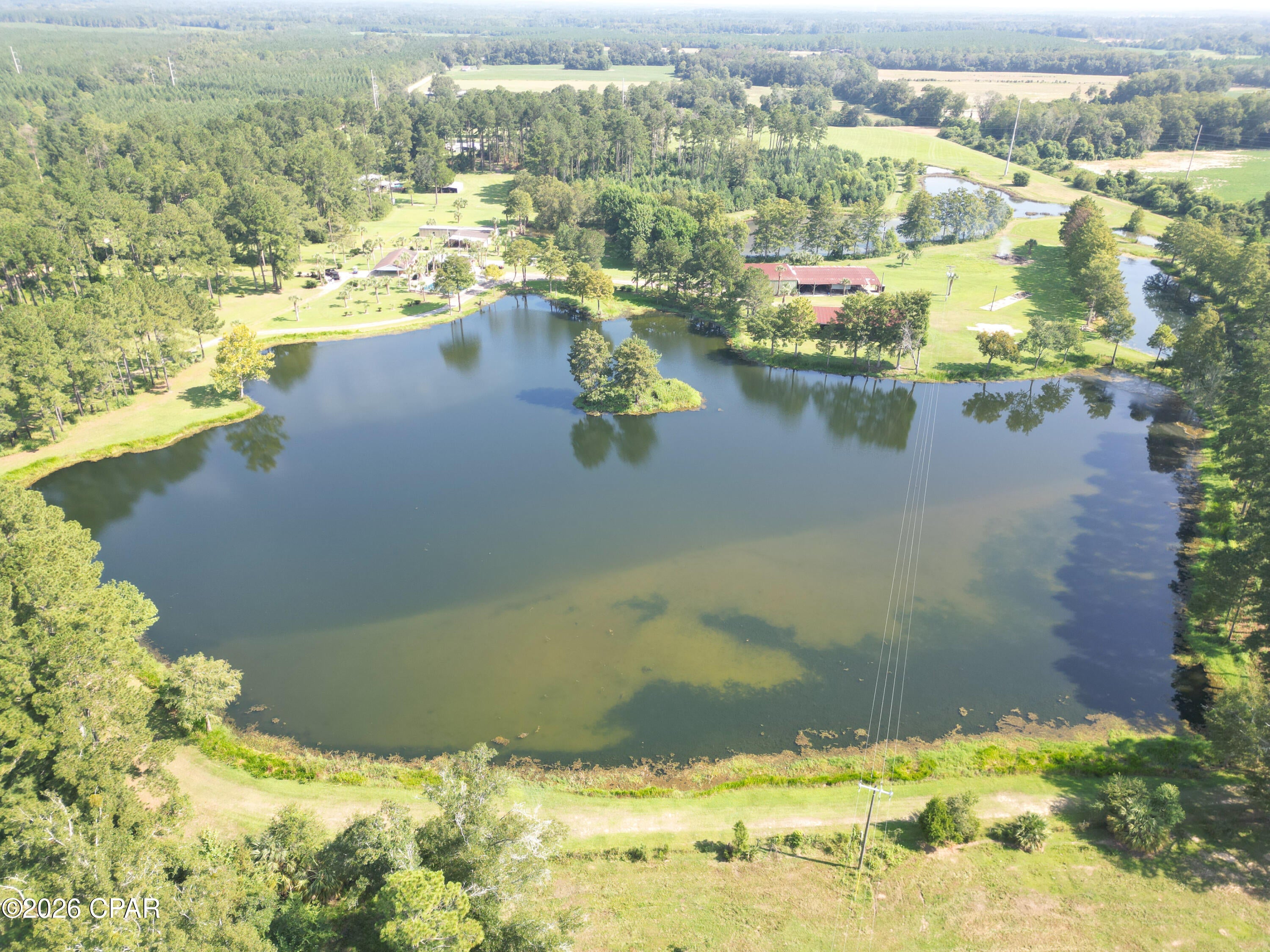 Welcome to Miles Palm Lakes! Tucked away in the country on 48 +/- acres in Jackson County, this is the kind of property where the days seem to move a little slower--where you can sit on the patio in the evening, fish your own ponds, and enjoy the peace and privacy of country living. 
With five private stocked ponds covering approximately 12 acres, mature pines and oaks, fruit trees, established trails, and open acreage.  Miles Palm Lakes has a tremendous amount of character and charm.  The minute you step foot on the property you immediately understand why it has been a place that has been enjoyed and cared for over the years. The ponds are completely private, with no outside access, giving you a rare opportunity to enjoy your own fishing for bream, catfish, and bass, and without leaving home. One of the ponds is equipped with a 15 HP pump and 4-inch steel drop pipe installed approximately 175 feet deep, adding another valuable feature to the property.
And there is plenty of room here for more than recreation. The property includes approximately 7 acres of tillable land, a 4,800-square-foot greenhouse, two substantial barns, and a 1,080-square-foot brick home. The larger barn offers a 60' x 60' enclosed structure with a concrete floor and an additional 60' x 90' lean-to, while the second barn measures approximately 105' x 40' with open sides and a gravel floor.
The brick home has 3 bedrooms and 1.5 baths and is in good condition, with opportunity for updating to suit your taste. A large outdoor patio and outdoor kitchen create a natural gathering place for family and friends--whether it's a Saturday afternoon cookout or a quiet evening watching the sun go down.
For the outdoorsman, the property offers an exceptional setting to enjoy the land and everything it has to offer. Abundant wildlife, including whitetail deer, turkey, and other small game, can be found throughout the property, while an established trail system winds throughout. The trails provide opportunities for riding your ATV's, horses, hunting, or simply spending time outdoors with family and friends. 
Access is convenient without sacrificing the feeling of being away from it all. The property has dual access from Canary Road and paved Highway 169, with State Road 273 just a half-mile away. Graceville is approximately 4.5 miles from the property, and Dothan, Alabama is approximately 25 miles away.
There is also room to make this property your own, with numerous potential homesites throughout the acreage. For a family looking to stay close while still having their own space, Miles Palm Lakes could make an exceptional family compound. For someone looking for a private country retreat, an operational farm, hunting and recreational land, or simply a place to get away from the pace of everyday life, the possibilities are wide open.  Call today and schedule your private tour of Miles Palm Lakes.
Key Features
• 48 ± Acres of Private Jackson County Land
• 5 Stocked Private Ponds -- Approximately 12 Acres
• Partially Fenced
• 3 BR / 1.5 BA Brick Home
• 2 Large Barns with Additional Covered Space
• 4,800 SF Greenhouse & 7 ± Acres Tillable
• Abundant Deer, Turkey & Wildlife
• Established Trails, Mature Pines, Oaks & Fruit Trees
• Dual Access -- Canary Road & Hwy 169
• Multiple Homesites & Family Compound Potential