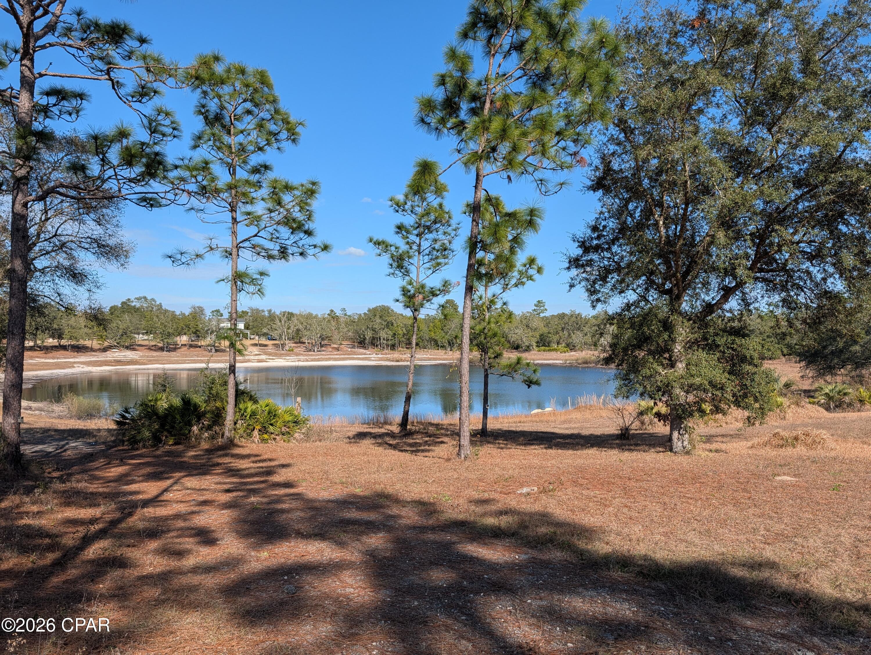 SEE TODAY! Owner is ready to sell. Custom site built single family home with downstairs (in-law apartment) on private pond/lake in Sand Hills area of northern Bay County - Located very near Elementary thru High School (Deane Bozeman School). Well over 3300 sq ft of total living space. The main (upper) floor is a single family home with 3BRs, and office, and 2 BATHs, offering open living area to kitchen/dining area with fireplace and great water views. Downstairs is oversized garage space and separate 1 BR apartment with own kitchen/living area and bath - it's an in-law style apartment great for parents, older child, or possible income.  There is additional ducted CHA (300-400 sqft) living space (Play Room) downstairs not included in the listed (total 3363 +/-) square footage. Two garages ~ a single wide that is 2-3 cars deep, and a separate double car garage. A great property for the car enthusiast/collector. In addition to the garage/storage space - there is an unfinished concrete walled (safe room) downstairs ideal for more storage, hobbies and/or storm safe room protection. Outside front covered porch. rear covered porch and balcony space. Hot tub on back porch - and whole house generator near property line are included but working condition(s) are not known and are being sold as is where is. There are detached covered tent/Quonset style parking structures. So perfect for the RV or car or boat enthusiast or hobbyist, or possibly the self employed needing extra covered storage space.  Fully adequate Central Heat is supplemented by a couple gas wall furnaces that home owner typically uses as option to central units. This property is being sold AS IS. SOME PHOTOS ARE OLDER FROM A PRIOR LISTING. Per legal description ~ land size is over 3 acres ~ But part of legal includes some submerged land beneath pond/lake. Actual dry land size may be nearer 1.5  to 2 acres. This home offers lots of options for a big family  with plenty of room to expand. A great location and property for those self employed or folks needing plenty of extra work space, storage, or for lots of hobbies, and room to grow. To reproduce this home and features in todays market would be very costly, so come see all the benefits and the gain to be had with this very well priced bargain.