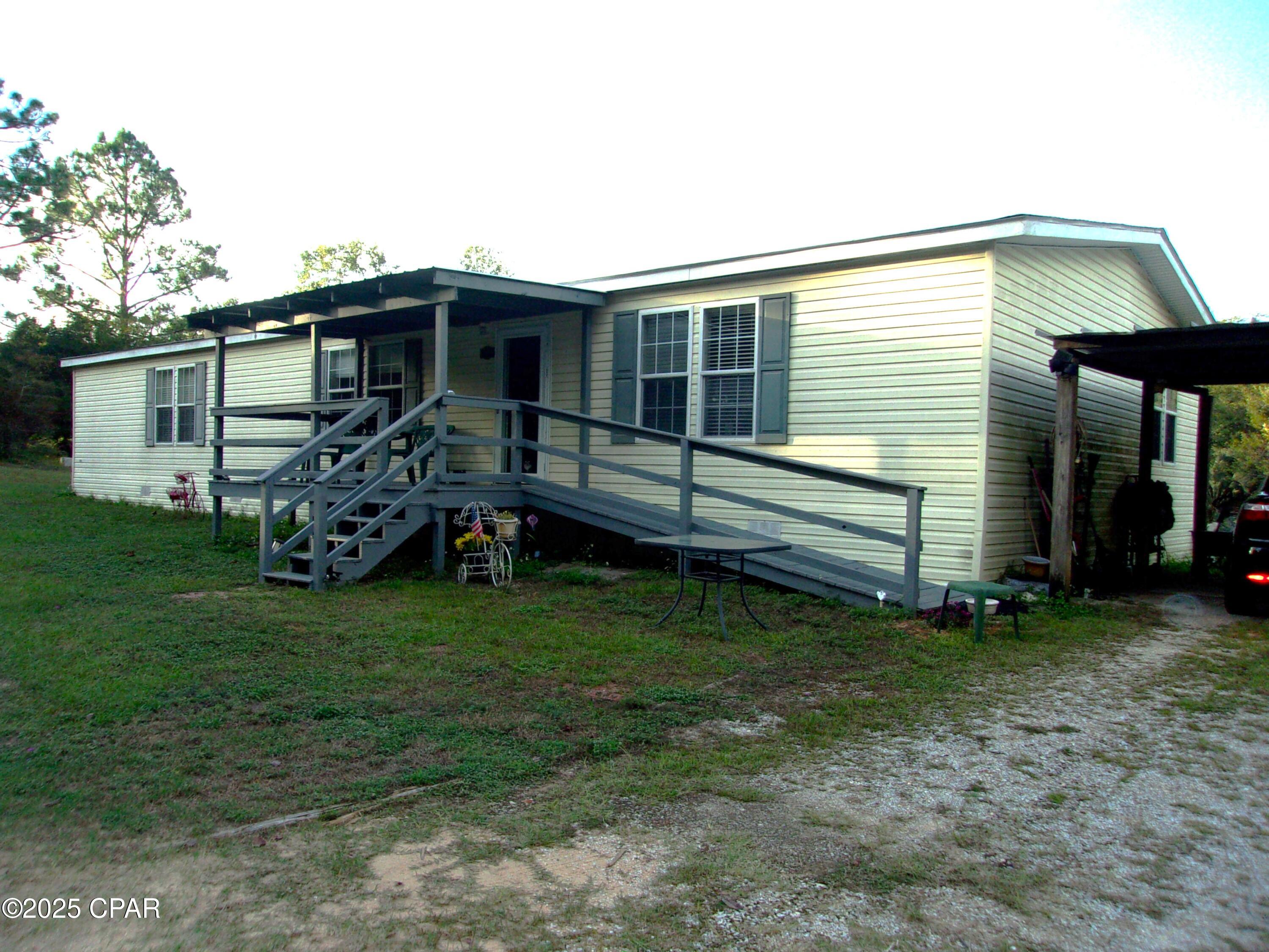 This custom-built double wide trailer on 2.8 acres is a fantastic opportunity for anyone seeking a charming, spacious home! The huge living room and open floor plan create a welcoming atmosphere, perfect for family gatherings or entertaining friends. The eat-at bar is a wonderful addition for casual dining, while the handicap entrance ensures accessibility for everyone. The master bedroom's impressive walk-in closet and adjacent sitting room provide a perfect private retreat, leading out to a lovely covered porch for enjoying morning coffee or evening sunsets. The property features a serene small pond, adding to its picturesque setting. With an old shop building along the highway, there's ample space for storage and hobbies. Located just 40 minutes from Panama City Beach, this home offers not only comfort but also the chance to enjoy one of the world's most beautiful beach destinations. It's a perfect blend of rural charm and coastal convenience!