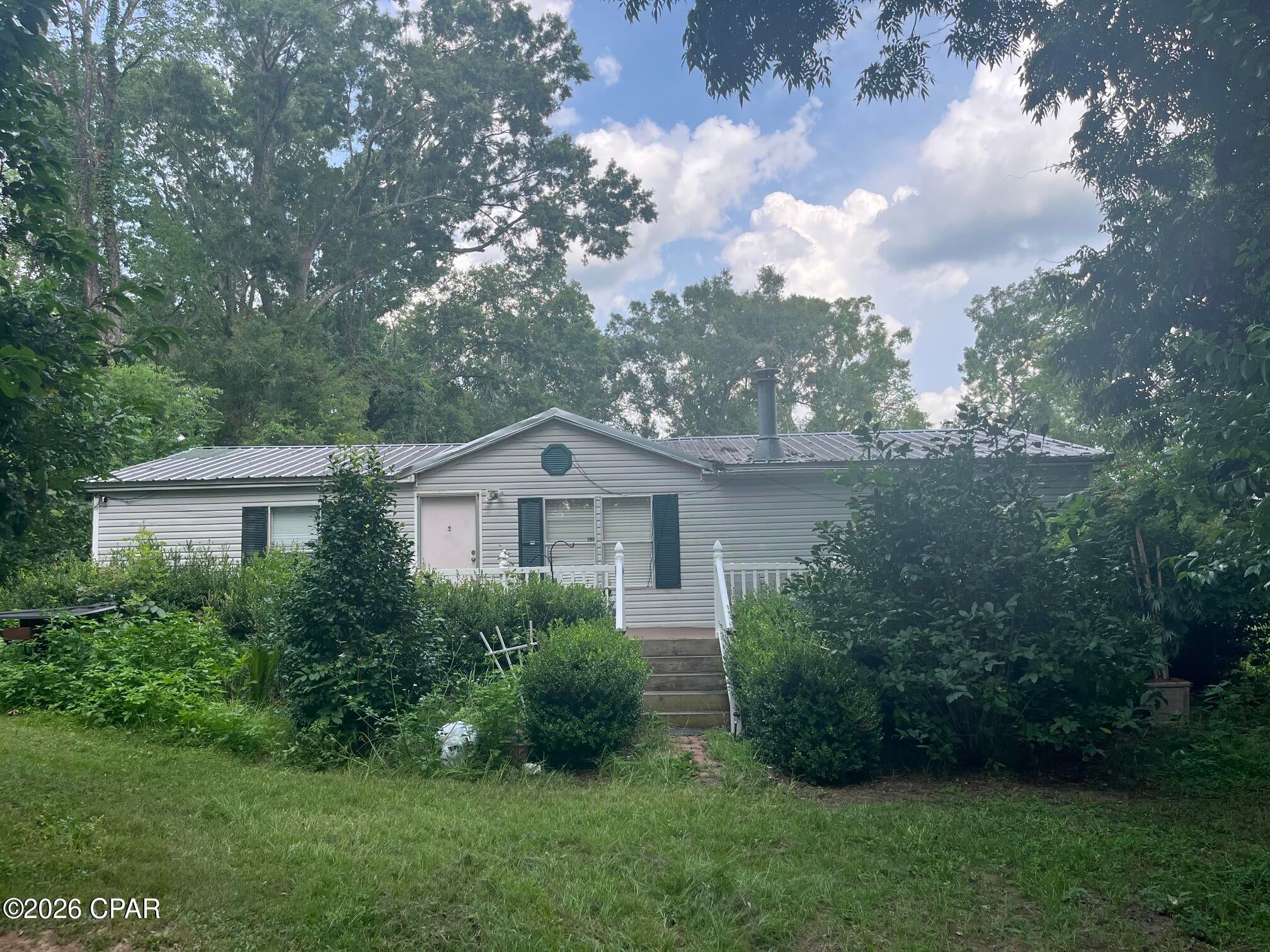 Set on 2 fully fenced acres, this 3-bedroom, 2-bath mobile home offers an incredible opportunity for those seeking a homestead-style property with room to grow. While the land is in need of a little care, the foundation for a productive and peaceful lifestyle is already in place. Each bedroom features a walk-in closet, and the living area includes a wood-burning fireplace, perfect for cozy evenings after a day spent outdoors. The front deck was redone just two years ago, providing a solid spot to enjoy your morning coffee surrounded by nature.

The land is thoughtfully laid out with second fenced-off section, making it ideal for animals, gardens, or rotational use. An older chicken coop and dog pen are already on the property, and a lawn mower and chainsaw convey, helping you bring the land back to life. For added peace of mind, six security cameras will remain with the home.

This property truly shines in its established plantings and fruit trees, a rare find for homesteaders. The land features Banana trees, Japanese and Red Magnolia trees, Sago palms, Pink Roses, fresh mint, Blue Hydrangeas, Azaleas, and multiple Pecan trees. Fruit-bearing plants include 3 Peach trees, 2 Pear trees, 3 Fig trees (including a yellow fig), Plum tree, Pomegranate tree, Persimmons, Blueberry bushes, Apricot tree, Yellow and Red Cherry trees, and a Lemon tree. Some plantings are currently in need of attention; but with time and care they could flourish into a productive, beautiful landscape.

The back portion of the property includes fallen trees and brush, offering an excellent opportunity for clearing, firewood, or future expansion. Whether you're dreaming of a self-sustaining homestead, hobby farm, or peaceful country retreat, this property provides the land, layout, and potential to make it your own.

Furiture being sold separately.