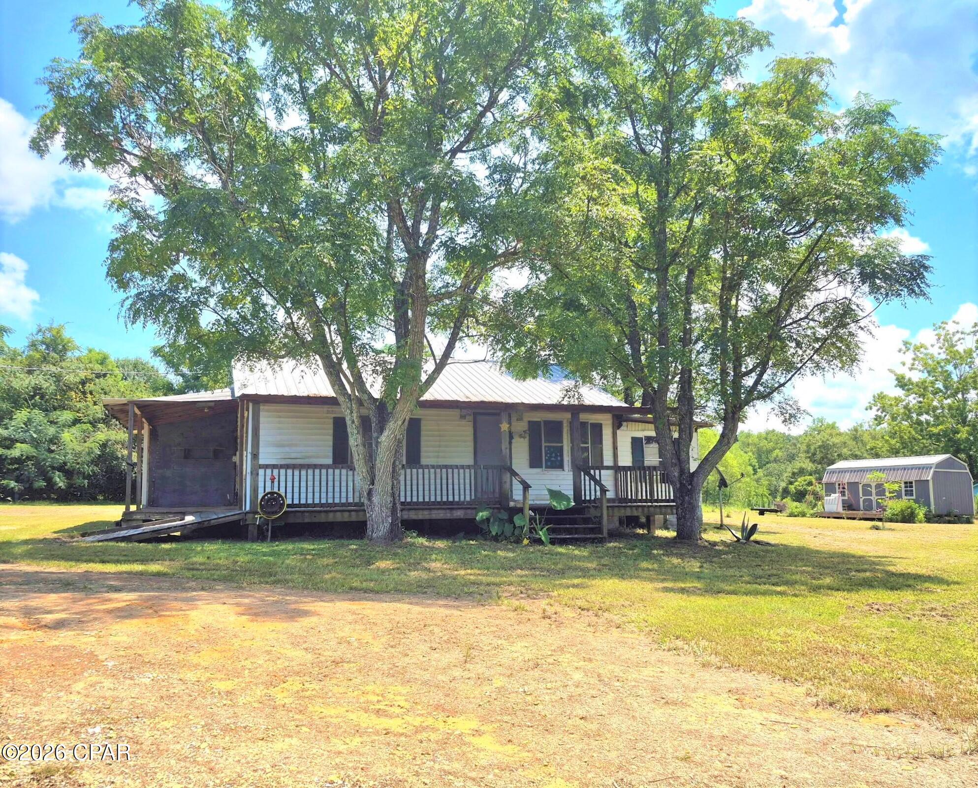 This two-bedroom, two-full bath home sits on a partially fenced .74/acre lot with road frontage. Large porches and a large yard for a pool, a garden, or your animals. Comes with a 12x20 shed that has a large deck and it's own electric/power pole. There is an hvac unit in place but condition is unknown.  This property is perfect for a homeowner willing to do some updates and renovations, or for an investor wishing to renovate or rent.  The flooring and the roof both appear to be in good condition but home will need interior paint, some wall repair, updated kitchen, etc.