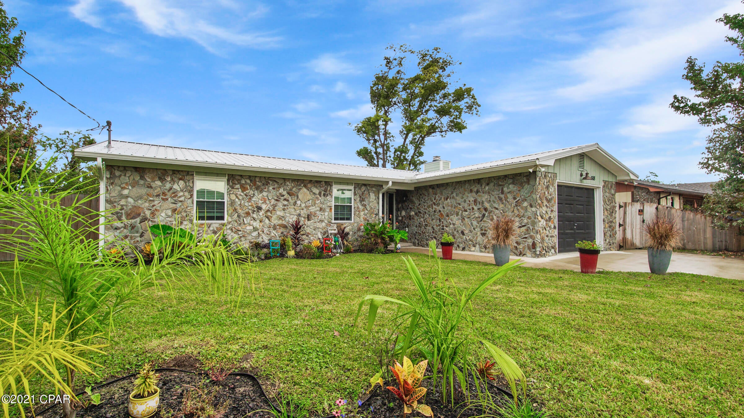 COLORFUL CURB APPEAL with detailed landscaping in the front & privacy trees along both sides of the house. Large fenced backyard with a section fertile soil for gardening.  Located in the heart of Lynn Haven close to essential shopping and dining. This home features an updated kitchen, Quartz counters, solid wood cabinets with soft-close drawers, matching stainless steel Whirlpool appliances, & tile flooring throughout the living areas. The open space concept includes a convenient island that opens to the living room featuring a stacked stone fireplace.  Bathroom's have been updated with vanities and faucets. Single car garage includes a washer and dryer. Schedule an appointment today.