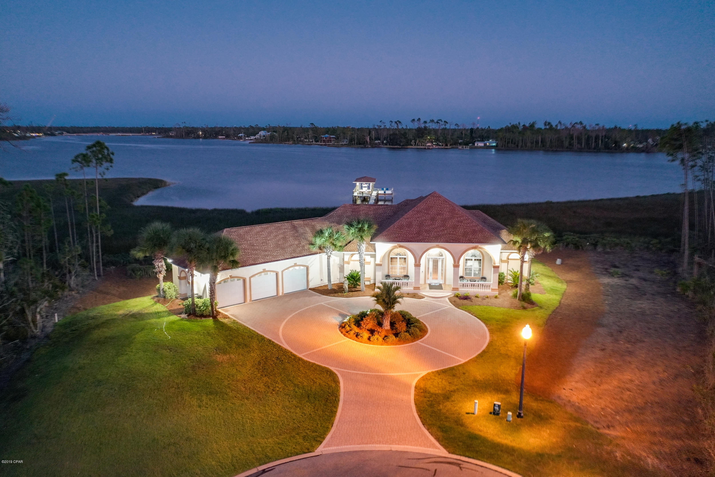 This one of a kind home is a must see! The moment you walk in you'll know you've found your paradise. The attention to detail in this custom-built home was beautifully done by one of Bay County's most well-known and recognized builders. From the brick paver driveway, to the lush landscaping and Mediterranean exterior feel, this home will have you ready to move in the moment you drive up. With almost 2,800 sq.ft of heated and cooled space PLUS approx. 475 sq.ft. of outdoor patio space (both open and enclosed areas) this home is perfect for entertaining the family, friends, and neighbors. And for you guys... a 3 car garage with over 750 sq.ft of space! As you walk in the front door you'll immediately notice one thing.... an amazing view! The best part, every room of this house has an amazing view!!! With 12 ft ceilings, 10 ft doorways, tons of natural light, and a perfectly laid out open floor plan this home feels larger than life. The complete list of upgrades and special features of this property can be provided in our Island Ct. Buyer's Guide. Just a few of the items you'll read are the fact that this property sits on over a half acre with more than 200 ft. of water frontage, a 260 ft dock that features a 20,000 lb covered boat lift and an underwater lighting system at the end of the dock, plus surround sound in the living room/screened-in porch & garage. If you're a fisher, boater, or just love relaxing days on the water this home is for you. Being just minutes to both the open Bay and the Gulf, your fun water days are limitless. This gated and serene community also features a Boat/RV storage, pool, and boat ramp/dock. Don't hesitate to reach us for more information.  We will be providing additional pictures soon!
