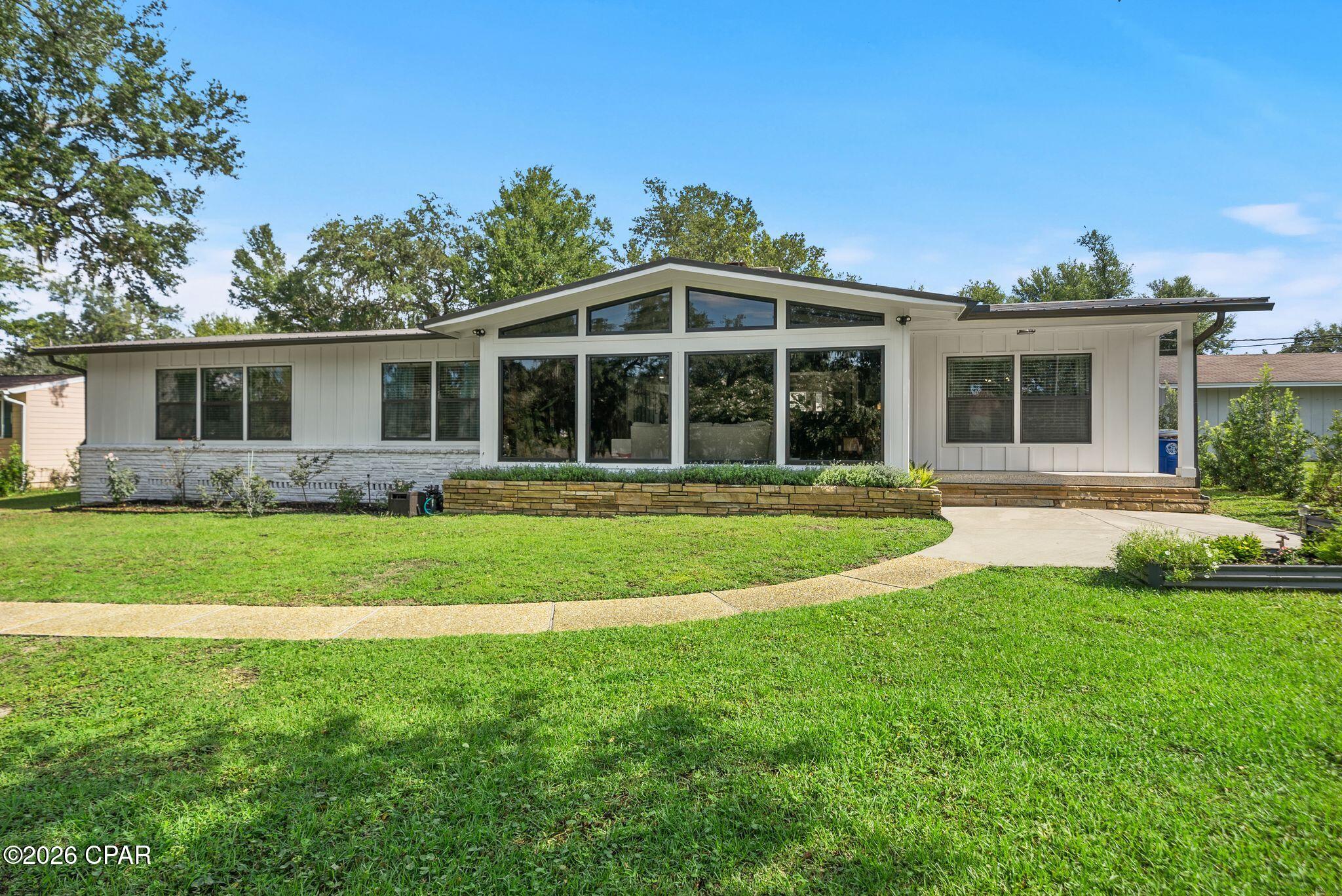 Sitting high on a hill, beneath hundred year old oak trees and on an over 1/3-acre homesite with NO HOA, this 3-bedroom, 2-bath mid-century modern beauty sits directly across from the water in one of Panama City's most historic neighborhoods...The Cove. 

And this isn't a ''close to downtown'' home where you still need to get in the car to go everywhere. This is walk-to, bike-to, golf-cart-to booming Downtown Panama City. Cruise the oak-canopied streets to Trigo San Francisco Style Deli for lunch, grab a coffee (or crepe, or glass of wine!) at The Press, or park the golf cart at History Class for a cold local pour. Waterfront dinner at the St. Andrews Bay Yacht Club? Ten minutes by cart if you're a Member. Downtown's growing lineup of shops, live music, and the regular scheduled community activities like the Saturday Farmer's Market's make living in the Cove even better.

Step inside, and you're greeted with 2,298 square feet of single-level living with original mid-century modern character. Original terrazzo and heart pine floors run throughout and this is the kind of detail you can't recreate, only preserve. The living room is anchored by vaulted, beamed ceilings, gas fireplace, and clerestory impact windows that make you stop in your tracks with the natural light and beauty they bring to this home! The living room flows into the dining room that connects to the kitchen for easy everyday living and easier entertaining. There is a charming light-filled, breakfast room off the kitchen that offers backyard views and the gas fireplace, as well. A large laundry room, home office and storage room are also located off the breakfast room and near the entry to the attached 2-car garage. The 2-car garage is a RARE find in the Cove and with alley access and additional parking, you're going to love the storage and parking for all your friends, family and their golf carts and cars! 

The kitchen was fully reimagined in 2022 with a new, functional layout, gas cooktop, wall oven, microwave, refrigerator, custom cabinetry, electrical, plumbing and marble countertops. The roof was installed in 2020, the exterior was completely renovated in 2024 with hardie board siding and the HVAC system was installed in 2025. 

The primary suite is a true retreat with a large bath, separate shower and toilet area and a large walk-in closet. The other two oversized bedrooms give real breathing room, including larger than typical closets in the Cove. A guest bath is easily accessible from the hallway for both guests and two guest bedrooms and is a fun nod to the mid-century modern design!

This home offers NO HOA and is just a rare mid-century gem, perched up high on a hill, in a charming neighborhood where the water's across the street and downtown's a golf cart ride away. If you're ready to start really living in the Cove, this mid century modern beauty is move-in ready for you to call home!