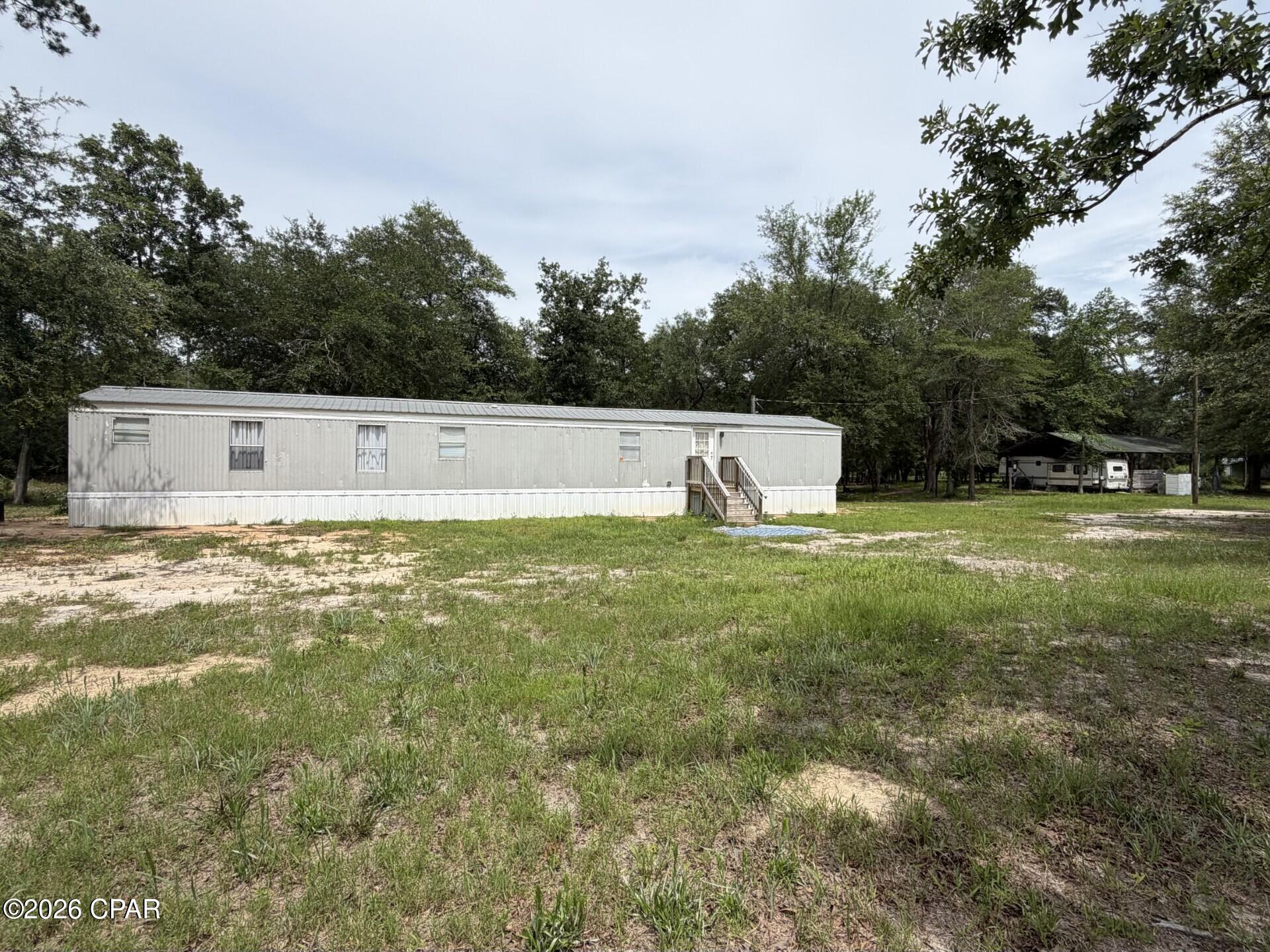 Escape to the peace and privacy of country living with this 2-bedroom, 2-bath home situated on 11.7 beautiful acres in the quiet community of Sneads, Florida. Surrounded by mature trees and open space, this property offers the perfect blend of comfort, functionality, and seclusion.

The home is nestled among picturesque land that provides exceptional privacy and plenty of room to enjoy the outdoors. A 20' x 30' pole barn equipped with electricity offers endless possibilities for storage, hobbies, equipment, or workshop space. Adding even more value, a camper will convey with the sale, making it ideal for guests, recreation, or additional living space.

Thoughtful improvements include a water filtration system installed on the main water line and solar lighting displayed near the barn. The property is partially fenced, and the entire perimeter is already marked with T-posts installed approximately every 20 feet along the property line, providing a head start for future fencing projects.

Whether you're looking for a private homestead, hobby farm potential, or simply a peaceful retreat away from the hustle and bustle, this unique property offers endless opportunities to make it your own. Enjoy the serenity of rural Florida while still being conveniently located near local amenities. Don't miss your chance to own this slice of country paradise!