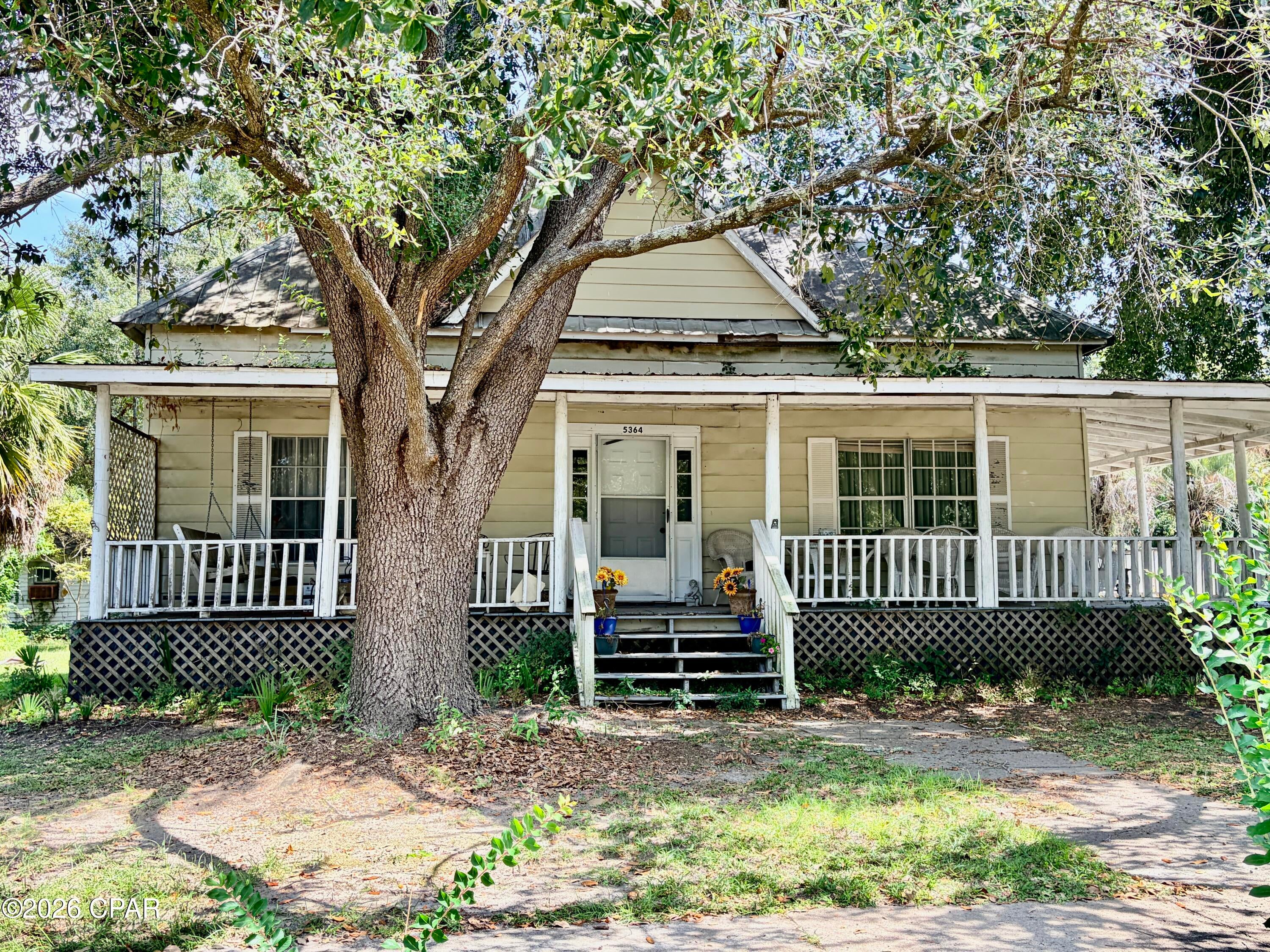TWO HOUSES, right on the main street of Graceville, FL, 1 block off of Hwy 77,  within walking distance to the Oyster Bar, Grocery Store, City Hall, Friday Night Lights, the sandwich shop, local bank, downtown and all things that coincide with the small-town vibe. Enjoy the big wrap-around porch and a half acre of land, with an additional  2 bedroom/1 bath cottage, a detached garage, storage shed/playhouse and lots of beautiful lawn space, flowers and majestic oak trees on a corner lot.  Inside the main house you'll find 3 very large bedrooms, 2 full baths, plus 2 half baths. Yes, all 3 bedrooms have their own private bath. (That's a total of 5 bedrooms and 5 baths on property). Plus there is a spacious living room and separate dining room.  There is a screened porch on the rear of the house, accessible via the lovely, country kitchen. The 2nd house is a small cottage on 9th Street with 2 bedrooms and 1 bath, (no power or water connected) that is currently being used for storage.   Get to know Graceville, a small town  in North Florida of approx 2300+/-  people, near the Alabama  border, but only 12 miles from the Chipley SuperWalmart and the NW Florida Hospital. The cost of living is approximately 18% below the national average and the laid-back lifestyle is a given.  Do not delay, make an appointment to see it because the potential is endless with this historic, family home.  The Seller is in the process of packing 35 years of homestead and there are boxes, but we can all look past that to see this gem of a property.  (All info is approximate and anything that is important to buyer, should be verified by buyer.)