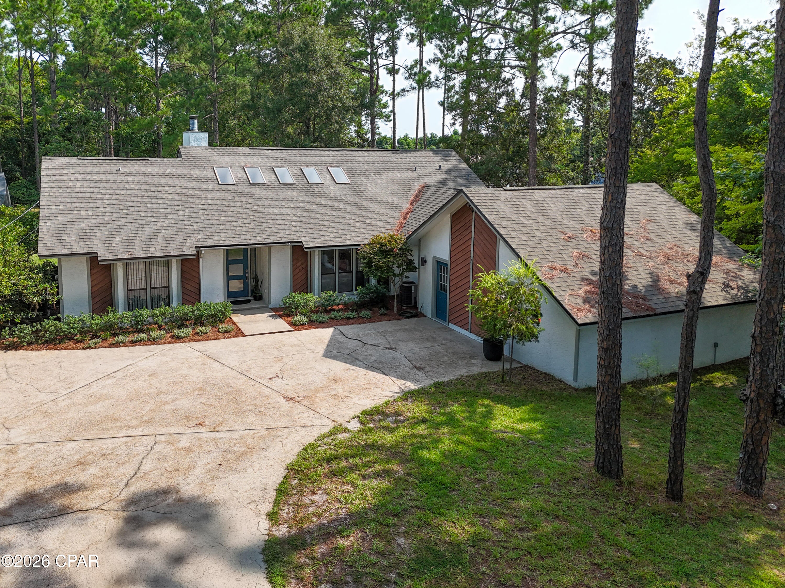 Welcome to the charming custom home situated on a rare one acre nicely maintained wooded Panama City Beach lot.  Less than one mile to the water and all the beach activities while remaining very private.  Full of natural lighting in its vaulted spaces from skylights as well as solar tubes in the bathrooms.  Totally renovated kitchen with easy care white quartz surfaces, abundant storage space and  lots of counter surface, large island for entertaining and baking lots of cookies! And as a bonus, the microwave, refrigerator, dishwasher, and the washer & dryer are all included. Renovated bathrooms include quartz counters, custom cabinets and tile floors. Double split bedroom floor plan with a cozy family room off of the kitchen adds extra space for family activities.  True wood-burning fireplace with a large custom mantle in the great room which include the SmartTV and sound system. Extra's include a 20x40 garage/work area with an open attic with tons of storage area., a 8x16 cottage with electric including a 4x8 porch and more storage area.! Other goodies: New roof in 2019, new fencing in 2020, new HVAC units (2)replaced in 2020, new Whirlpool appliances in 2020, bathrooms,  kitchen, Back Patio, front door  renovated in 2020.  Home was connected to city sewer in 2025. All room measurements are approximates.
