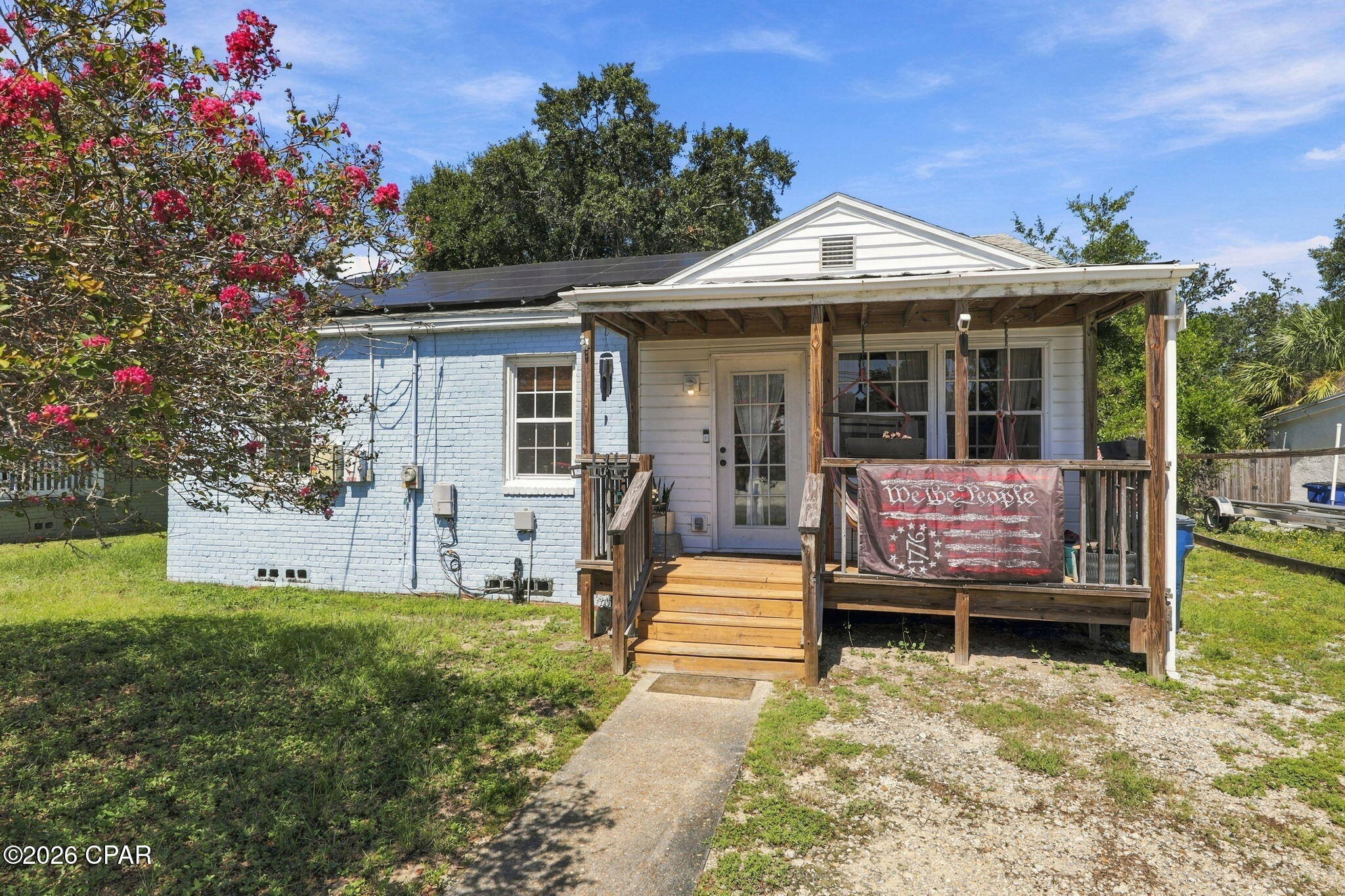 Updated 1942 painted-brick cottage in Oakland Terrace on a fenced lot 150 feet deep, with rooftop solar, a renovated kitchen, and an enclosed front sunroom that adds real living space beyond the 874 heated square feet. You are 4 minutes from the St. Andrews Marina and Historic St. Andrews, 5 from downtown Panama City, 6 from Ascension Sacred Heart Bay, and a half-mile walk from Oakland Terrace Park's pickleball and tennis courts, playground, and walking track.

The covered front porch leads into the sunroom, a brick-walled, window-lined room with a glass entry door that works as a plant room, office, or second sitting area. A sliding barn door opens to the living room, and hardwood floors continue through the dining area and all three bedrooms. The kitchen has been redone with blue cabinetry, butcher-block counters, open shelving, shiplap walls, and stainless appliances, and it connects to a dedicated laundry room with its own door to the backyard.

Out back is where this lot separates itself: deeper than many nearby lots, fully fenced, shaded by mature oaks, with a rear deck for grilling and a storage shed for bikes, kayaks, or tools. The rooftop solar array (buyer to verify ownership and system details) sits on a home that already has central heat and air and ceiling fans.

Three bedrooms and a full bath with tub-shower combo, all on one level, no HOA, and FHA, VA, and conventional financing welcome. Naval Support Activity Panama City is about 14 minutes away, Tyndall AFB about 21, and the Gulf beaches at St. Andrews State Park about 18.