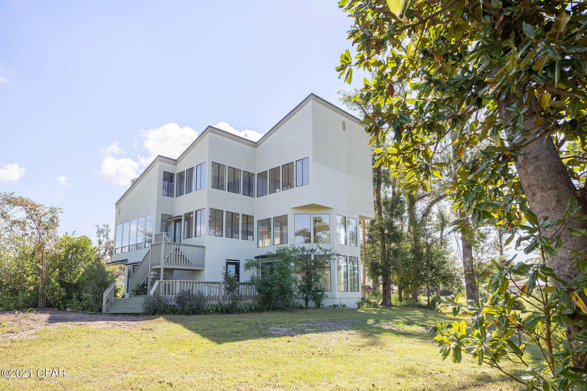 CURRENTLY UNDER CONTRACT, SELLER ACCEPTING BACKUP OFFERS There will NEVER be a lack of light in this custom built Lynn Haven home close to everything in College Point! Natural light floods in from over 65 large windows from every corner of this house! Situated on 1.65 acres, not only does the home feel open and bright but the entire property does as well. This home has been gutted and completely remodeled from the studs out, everything inside and out is completely new. LVP flooring, custom kitchen, upgraded lighting, wrap around decking, and the entire 3rd floor dedicated to a huge master suite and custom master bath with dual walk in shower and stand alone tub. Plenty of flex space and storage space in this home to fit your needs or vision. Yard is very large and is on a corner lot with plenty of options for a pool or beautiful custom landscaping... there's plenty of space to spread out here without neighbors close. Home has new roof, new stucco, and fresh paint. There is a pull through driveway with a large overhang that will accommodate a full size camper or RV underneath. This home is ready for new owners and is truly a must see so call today and schedule your showing!