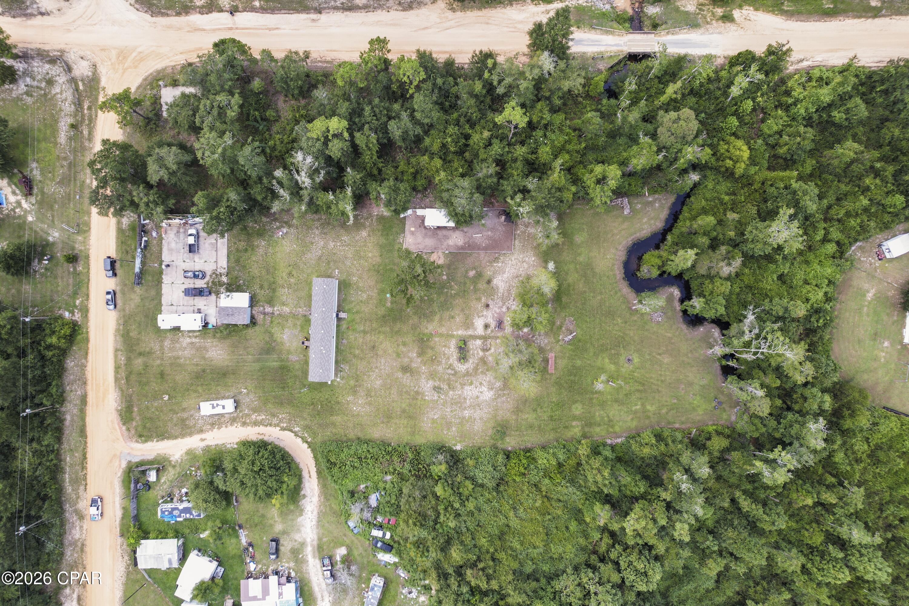 1.6 ACRES ON BEAR CREEK WITH A NATURAL SPRING, RV HOOKUP, DEEP WELL, NO HOA & MORE! If you've been searching for peaceful country living with acreage, water, and room to spread out without being too far from town, this property is a rare find. Situated on approximately 1.6 acres with Bear Creek running right through your backyard, this incredible property even features its own natural spring. Imagine spending your afternoons fishing for catfish and bluegill, catching crawfish, or simply relaxing by the creek and enjoying the peaceful natural surroundings. The 2024  2 bedroom, 2 bath mobile home has been exceptionally well maintained, and still looks and feels like new. Cathedral ceilings create an open and spacious feel, while the bedrooms and bathrooms are surprisingly generous in size compared to many homes of this type. The kitchen offers plenty of counter space and cabinetry, a pantry, breakfast bar, and gas range. The spacious primary suite features a walk-in closet and private bathroom with BOTH a soaking tub and separate shower. All major appliances, including the washer and dryer, convey with the home. Outside, this property offers features that are hard to find all in one place. A massive 60' x 70' parking pad provides plenty of room for vehicles, boats, trailers, or an RV and includes an RV hookup with a separate power meter. The property also features an approximately 280-foot deep well and a 12' x 20' storage shed with power. A second washer and dryer along with the freezer located inside the shed also convey. Looking for a mini-homestead setup? The existing chicken coop comes fully stocked with approximately 80 chickens, giving you the opportunity to step right into the country lifestyle. Enjoy the privacy and space of country living while remaining conveniently located approximately 20 minutes from Publix and 25 minutes from Panama City. The road is county maintained and graded regularly, providing a rural setting with maintained road access. Furnishings and a two-year-old Cub Cadet riding mower may also be negotiable with an acceptable offer. With 1.6 acres, Bear Creek frontage, a natural spring, fishing right in your backyard, RV accommodations, a 280-foot deep well, powered storage, a homestead setup, and a nearly-new home, this property offers a combination you simply don't find every day. Bring your RV, chickens, fishing poles, and love of the outdoors--your peaceful country retreat is waiting!