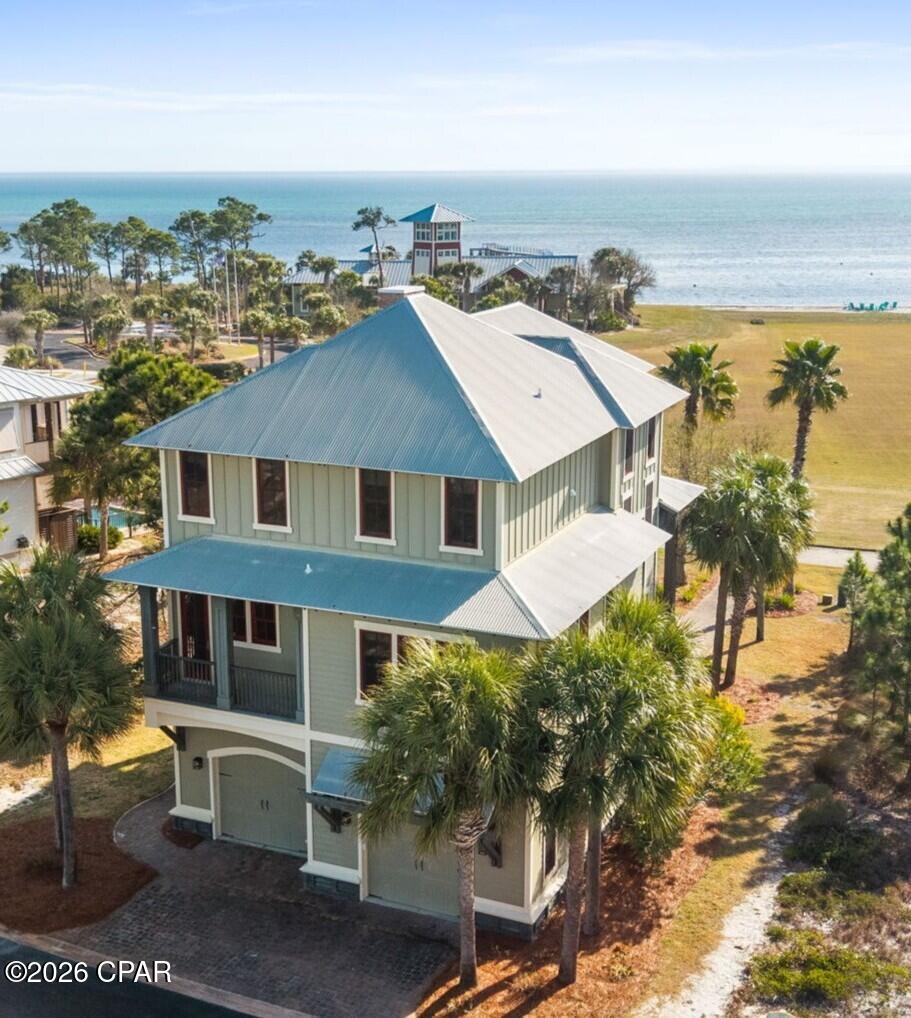 REFINED COASTAL LIVING!! Panoramic Bay views take center stage from this architecturally crafted Ovation home, perfectly positioned in the heart of the crescent across from the clubhouse. With sweeping water vistas stretching across the horizon & peek-a-boo Gulf views beyond, this home captures the very best of coastal living from the expansive decks. Morning sunrises shimmer over the Bay, while evenings bring painted skies & cool breezes that make outdoor living unforgettable. As one of the first thoughtfully designed homes built in Ovation, it set a precedent for quality construction, attention to detail & timeless architectural character within the neighborhood. From the moment you step inside, the craftsmanship is undeniable. Brazilian walnut wood floors anchor the living areas with warmth & richness, complemented by stained Andersen 8' all-wood panel doors & extensive custom molding & trim throughout. African granite counters & custom tile elevate the kitchen & baths, while a striking custom glass tile gas fireplace adds both beauty & ambiance to the main living space. Natural light pours through numerous unique windows, continuously framing those panoramic Bay views. The kitchen is designed for gathering & everyday enjoyment, featuring a gas cooktop, built-in ovens,  stainless appliances & a generous island perfect for entertaining. Two master suites provide luxurious flexibility, including a serene primary retreat with private deck access overlooking the water. The covered porches offer incredible vantage points to relax & unwind. Just steps from the clubhouse, infinity-edge bayfront pool, fire pit, fitness center, tennis & pickleball courts make this an ideal homesite. Tie up at the day dock, kayak across the Bay, fish the afternoon away, then bring your catch home to grill. Ride your bike or golf cart over to the Gulf-side pool & beach access for a sunset stroll. This is coastal living at its finest. Call for your private tour & LIVE THE BEACH LIFE!