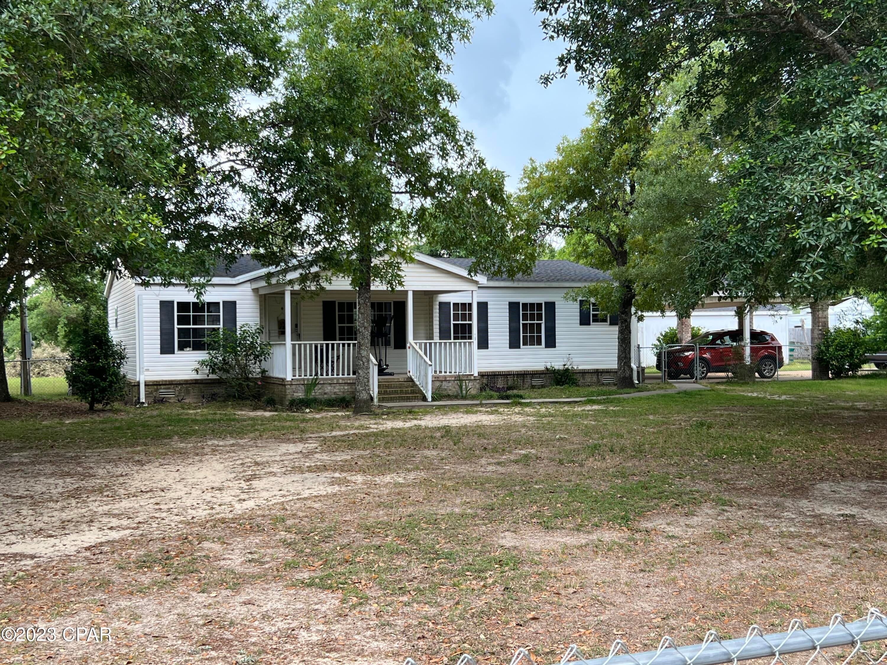 Impressive 3/2 double wide with 2 car carport built on, home has brick skirting, New roof in 2020,  Long concrete drive way, big master bedroom with huge master bath and closet. Double master sinks.  All newer laminate flooring through out the home. Split bedroom design for Master privacy. Plenty of kitchen cabinets with deep sink and SS refrigerator. Outside is a 12 x 18 back deck, 24x36 pole barn, 2 additional storage buildings, and plenty of shade.  Compass Lake is only 2 miles south for excellent fishing, swimming or boating.  Hwy 231 is only 1 mile away. Panama City Beach is less than 1 hr drive and is known for the one of most beautiful beaches in the world.This home shows very well. Make your appointment today.