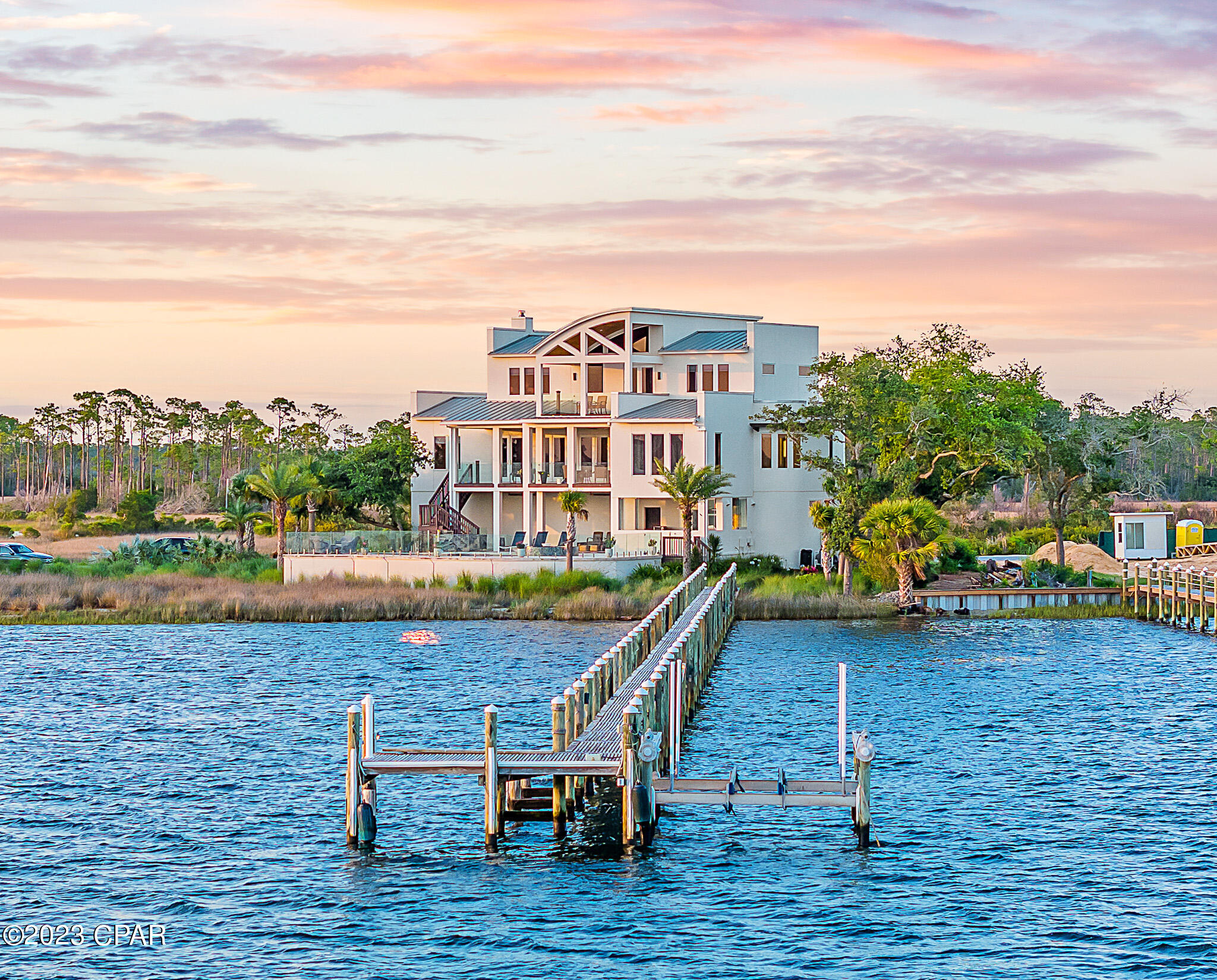 Nestled on the shores of North Bay, on a private island just off the coast in northwest Florida, sits a truly quiet and peaceful oasis of natural tropical beauty and a home of remarkable contemporary and modern architecture. This soaring three story estate was masterfully designed and brought to life by renowned Architect J Michael Hunnicutt and built by Rita Jones Construction. Spanning three levels with over 5,000 square feet, every room provides incredible waterfront views and offers expansive outdoor living with bay view covered porches on each level. With deep water and the Gulf of Mexico just 10 nautical miles away with NO idle speed zones in between, this luxury residence provides endless opportunities for fishing and boating enthusiasts with a private 350' dock.

 
Upon initial approach to the private island, you are welcomed by natural native landscaping and the soothing sounds of the Bay. This impressive 3 story home is framed by picturesque views of the Bay, surrounded by cascading sounds of the saltwater pool and spa which seem to blur the line between indoors and out.  The home includes a fully equipped outdoor summer kitchen and an 18' deep covered patio.  The summer kitchen is an entertainer's tropical dream. The custom kitchen cabinets are built of solid walnut sealed in marine grade varnish. The impressive cooking areas feature an all-Lynx luxury appliances package including a grill with rotisserie, dual cooking burners and power burner, and Lynx warming oven. Caesarstone quartz countertops and waterfall island are perfect for cocktails and entertaining. Situated on a large homesite and encompassing all that Florida's waterfront lifestyle has to offer, the deep-water dock will host your boat year-round and allows for residents to continue to pursue their waterfront dreams with boating, kayaking, and fishing! 

 
Step off the tumbled cobblestone paver driveway onto the travertine marble tile front entry steps to the stately front door and foyer framed with a custom Mahogany wood door with artistic blown glass. As you enter the main level, you'll be immediately drawn to the waterfront views at 23' elevation and a great room that offers tranquility and relaxation. A modern linear fireplace surrounded with marble and slate tile creates warmth in the space while framing full-glass French doors that lead out onto a covered patio overlooking both pool and Bay. From here you can take in gorgeous year-round sunsets as they sink into the horizon each evening. The second level anchored by the great room is completed with a stunning formal dining room, a remarkable powder room with Onyx walls and flooring with custom stone pedestal sink and a junior suite overlooking Bay and pool complete with full bath, walk in closet, and Juliet balcony. Polished travertine tile is found throughout the main floor and leads into the waterfront breakfast nook and Chef's kitchen.  

 
The fully-equipped kitchen boasts custom slab walnut cabinetry with soft-close hinges and pull-out drawers, 48'' Thermador Professional 6-burner gas range with double convection ovens and griddle, Electrolux convection microwave oven, warming drawer, Viking range hood and full-size Electrolux refrigerator and freezer. The kitchen features Caesarstone Quartz countertops and the oversized island that seats 4 is adorned with sleek waterfall edges as well as filtered cold and instant hot water at sink, pot filler at the range and a wet bar with wine refrigerator all designed with entertaining in mind! Adjacent to the kitchen is a 16'x10' walk-in pantry and laundry room with stunning granite countertops, custom cabinetry, elevated washer and dryer, built-in desk, shelving and sweeping views of the island. Moving toward the Bay through the kitchen, you'll retreat into the primary suite. Overflowing with natural light and shimmering blue water from the Bay, the primary suite is luxurious and calming with custom walnut cabinetry with Swarovski crystal knobs, radiant heated Italian porcelain tile floors, an aquatic air tub gracefully accentuated with Bay views, an incredible, spa-like curved Grohe walk-in shower made from tumbled marble pebble rocks with 3 body jets and 2 hand showers and a large 14'x9' closet in the primary suite featuring fully enclosed cabinetry.  The primary suite also provides access to the spacious covered waterfront patio with fireplace and access to saltwater pool and spa below.  
 
Perched atop the third floor is the perfect place to admire the distinctive architecture of the soaring tongue and groove barreled ceilings and the famed Emerald Coast sunsets each night. This level offers a 19x16' loft living area with cork flooring and an office with French doors and private waterfront patio adding an elegant touch to this alluring space. Two large en suite guest bedrooms are located on the third level, each with walk in closets, walk-in shower, custom cabinetry, and radiant heated Italian porcelain tile floors, providing ample privacy and luxurious finishes. 
 
Sitting at 11' elevation, the first level of the home features a 35'x24' - 4 car tandem garage with doors that have a 150-mph wind rating. A separate 15'x10' workshop space in garage is ideal for the car enthusiast and boat lover. Step out of the oversized garage into the 
mud room and 26'x16' media-game room. This oversized entertaining area is off the pool and covered patio and features a full bath and fully equipped kitchen with built-in refrigerator, icemaker, dishwasher, microwave, granite countertops and walnut custom cabinetry. Imagine the memories that can be made here with days in the pool and nights watching movies and playing games. This floor also boasts a walk-in wine room with separate air conditioning system, double pane tempered glass door and custom shelving. The utility room is perfect for storage off the garage and media-game room and has a hidden "secret room" built for tornado and hurricane shelter. A unique feature of this home is the climate-controlled storage room. This heated/cooled room features hot and cold water, drain in the floor and a door to an enclosed outdoor area which could be perfect for the dog or animal enthusiast!  
 
The stately manor is built of cement filled concrete block walls, hurricane rated Anderson windows and doors, and frameless ½" tempered glass railing system around pool and porches for fully functional but unobstructed captivating views. A built-in generator fully powers the second and third floors of the home and there are high-efficiency heat pumps for each floor providing year-round comfort during the changing seasons. This rare offering combines luxury features with low maintenance like natural landscaping with a drip irrigation system on a programmable timer.  Another great feature for year-round comfort is a built-in automatic mosquito repellant misting system.  A modern outdoor LED lighting system and Deep Sentinel home security system are also notable features of this home. A new, standing seam aluminum roof was installed in 2019. Infrastructure on the island includes high speed internet, city water and sewer. Home has a personal buried 500-gallon underground propane tank. 
 
If you've been looking for an exclusive waterfront home with virtually 360-degree Bay views, then Northshore Islands is for you. This unique private island community represents an opportunity that is not to be missed. Inquire today to schedule a private viewing and start living the coastal life you desire. 

Visit www.4200northshoreislands.com for additional features, videos and information.