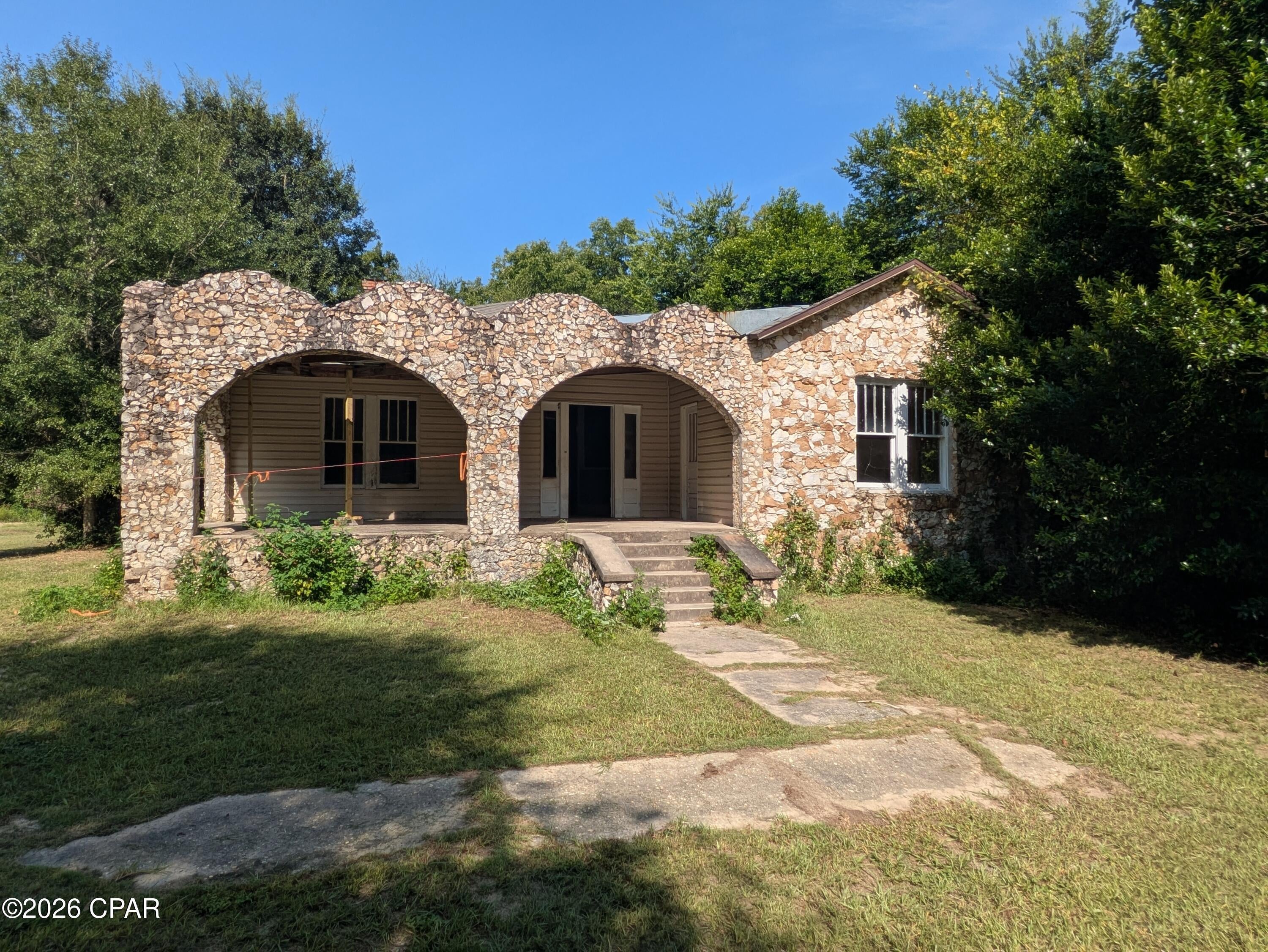 Investor Alert! Here is your chance to own a one-of-a-kind historic farm home. Beautiful and rare limestone cladding on the front of the home frames in the large covered porch. The owner stated the limestone was picked from the nearby farm over 100 years ago.  Inside you'll find solid wood doors and built-ins, large spacious rooms, multiple fireplaces, hardwood floors, and rustic charm. 

With multiple doors and connecting rooms, there are loads of options to configure however you like. 

Plenty of room for parking, and a carport provides shade at the rear of the home. Some landscaping cleanup will provide open views of the farmland behind the house. 

This home needs repairs and is sold as/is. There are some electrical & plumbing updates, including a new well pump. The roof was replaced in 2019. There is no permanent HVAC system. All fireplaces have been covered and condition is unknown.

Along the road is an original limestone rock wall that ran the length of the road frontage, it is overgrown and needs cleaning & restoration. 

20 Minutes to Marianna, FL and 10 Minutes to the Town of Malone. 

Info and dimensions are approximate, buyer to verify.