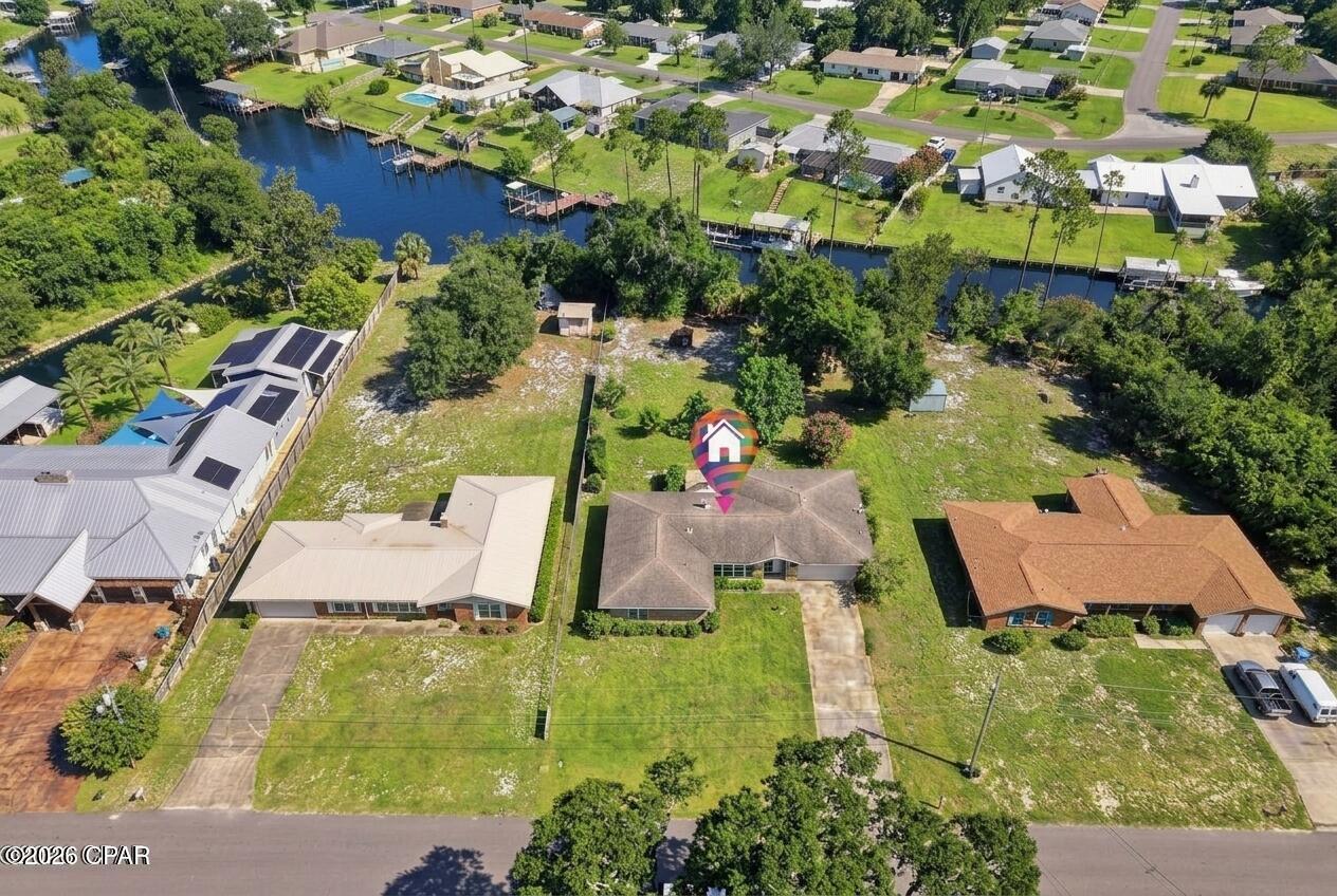 All-Brick Waterfront Home | Direct Gulf Access | Over ½ Acre | NO HOA | Exceptional Privacy

Rare opportunity to own over half an acre of private waterfront with no HOA and complete freedom to make the property your own. A dense natural tree line along the back of the lot creates exceptional privacy--you won't see neighbors across the canal, giving you a true sense of seclusion while still enjoying direct waterfront living.

This charming all-brick 4-bedroom, 2-bath home offers more than 2,400 sq ft of living space filled with natural light, new flooring throughout, and a fresh interior paint job. Approximately 100 feet of natural shoreline--one of the few remaining natural shorelines in the area--provides easy, soft access for kayaking and paddleboarding, plus a private dock for launching your boat.

Cruise less than 9 nautical miles to the crystal-clear waters and white sandy beaches of Shell Island, or head about 11 nautical miles through the pass to open water for deep-sea fishing. Panama City Beach is less than 3 miles away, Tyndall Air Force Base is approximately 15 miles away, and grocery stores and shopping are located nearby.

Inside
An open, inviting living and dining area centers on a cozy wood-burning fireplace. The kitchen features a breakfast bar, warm wood cabinetry, and granite countertops that flow into the formal dining space. You'll also find a dining nook, a dedicated formal dining room, and a versatile bonus space next to the living room--ideal as a home office or extra dining area. The spacious master suite includes a walk-in closet and a private bath with a walk-in tile shower. Three additional bedrooms share a full bathroom featuring a tiled tub/shower combo. A large laundry room makes daily living effortless.

Outdoor Living
Step outside to your private waterfront oasis. Enjoy the included hot tub, entertain around the built-in gas and charcoal grill, or gather at the firepit on cooler evenings. The expansive backyard is large enough for a pool, play area, or garden, with two storage sheds and a beautiful orange tree adding charm and fresh citrus. A sprinkler system covers the front and back yards. The home sits on a well-and-septic system with an instant hot-water heater under the sink. Roof is approximately 2017. All-brick construction.

This rare waterfront gem combines classic Florida charm, modern updates, natural shoreline access, unmatched privacy from the tree-lined canal, and unbeatable boating convenience--without HOA restrictions. Ideal as a primary residence, weekend getaway, or investment. All sizes, distances, and ages are approximate; please verify if important.
