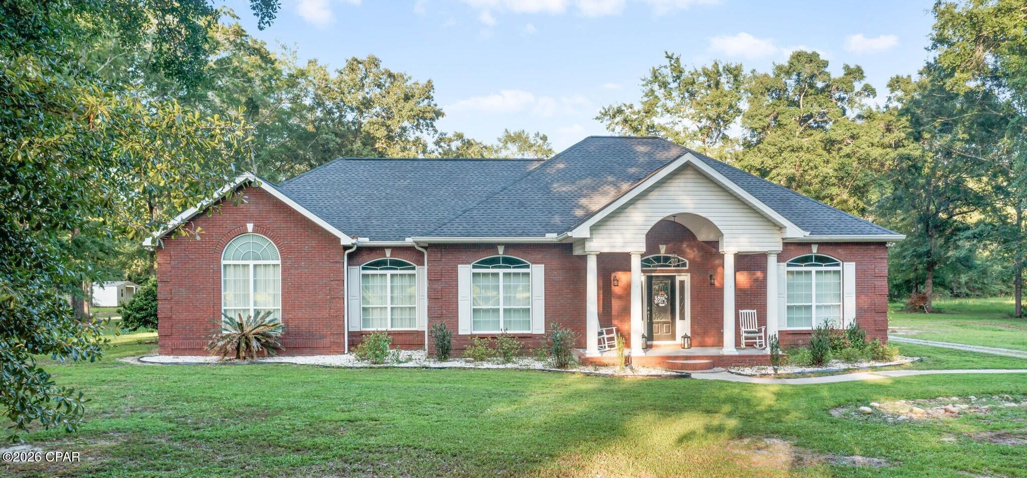 Timeless Southern charm meets peaceful country living on the highly desirable Falling Waters Road. Nestled on approximately 7.5+/- acres beneath a canopy of mature hardwoods, this beautifully maintained brick home offers the perfect combination of privacy, comfort, and functionality in a setting that feels worlds away from the hustle and bustle. Inside, you'll find a spacious open-concept layout designed for both everyday living and entertaining. The inviting living room is filled with natural light and centered around a cozy fireplace, creating the perfect gathering space for family and friends. On the opposite side of the fireplace, an additional living or sitting area provides flexible space for relaxing, reading, watching television, or entertaining guests. The kitchen features updated countertops, stainless steel appliances, breakfast bar, and ample workspace, all overlooking the main living areas to keep everyone connected. The generously sized primary suite serves as a relaxing retreat, showcasing a dramatic arched window, cathedral ceiling, oversized walk-in closet, and an en-suite bath complete with double vanities and a large walk-in shower. Two additional bedrooms and a full bath provide comfortable accommodations for family members or overnight guests. A bonus space currently utilized as a home office offers additional space. Step outside and enjoy the beauty and versatility of the acreage. A blend of open lawn and wooded surroundings creates a picturesque backdrop for outdoor recreation, gardening, animals, or simply relaxing and enjoying the peaceful views. The attached two-car garage offers convenient parking and storage, while the detached pole barn provides plenty of space for boats, equipment, recreational vehicles, or hobbies. Offering the tranquility of country living while remaining conveniently located near shopping, dining, schools, and everyday necessities, this exceptional Falling Waters Road property delivers the space, privacy, and lifestyle you've been searching for.