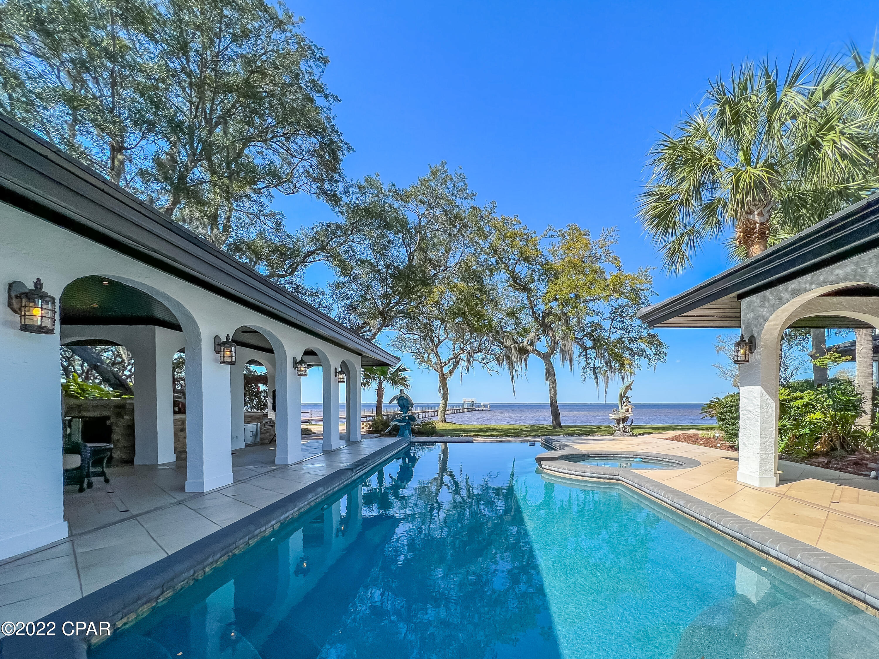 If luxury and relaxation on the water is what you seek, look no further! Approaching this Mediterranean inspired estate, you'll notice pristine landscaping to include fruit trees and camellias, a fenced in courtyard, concrete pool and hot tub, full outdoor kitchen, and multiple arched breezeways surrounding the home. Inside this grand home, we have an exquisite kitchen with Viking appliances to include an oversized refrigerator, 6 burner gas stove and griddle, double ovens, ice maker, dishwasher, and a built in Miele/cappuccino maker. We also have an array of cabinetry for storage with under cabinet lighting. Entering the living area, you will notice the gleaming walnut flooring and expansive space ideal for entertaining. See additional remarks for more! This living area is surrounded by windows for natural lighting, features a Grand Piano which conveys with the home, has an oversized gas fireplace, dining area, and a bar for serving guests. On the opposite side of the home, we have our bedrooms and attached 2 story casita home ideal for in laws or guests. Our large main suite features a fireplace, his and her bathrooms with walk in closets, and 4 sliding glass doors which open up to the pool and patio areas. Surrounding the pool outside, we have our gorgeous pavers, patio space, fire pit, and 500 foot dock with observation deck, boat lift, and pontoon lift. Our attached oversized 3 bay garage is heated and cooled and serves as entertainment space, workshop, and more! Roof is new March 2022 and 4 AC units are new 2019. This home is also equipped with a whole home generator and artisan well. This truly is an incredible opportunity! Furnishings negotiable except owner's primary suite furniture. Measurements approximate. Buyer to verify if important.